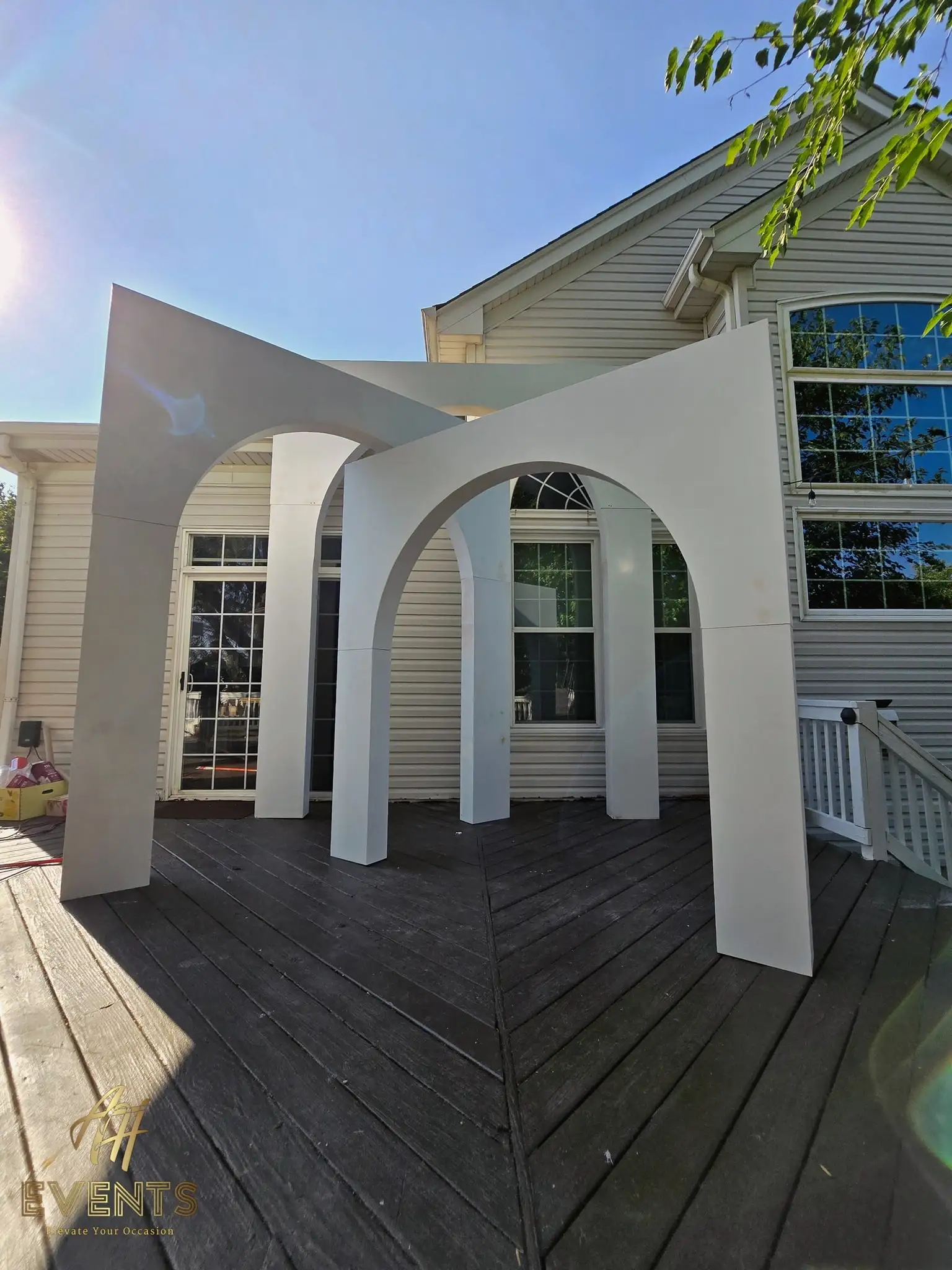 Three nested white volumetric arches of increasing size set up on a backyard deck in the sun