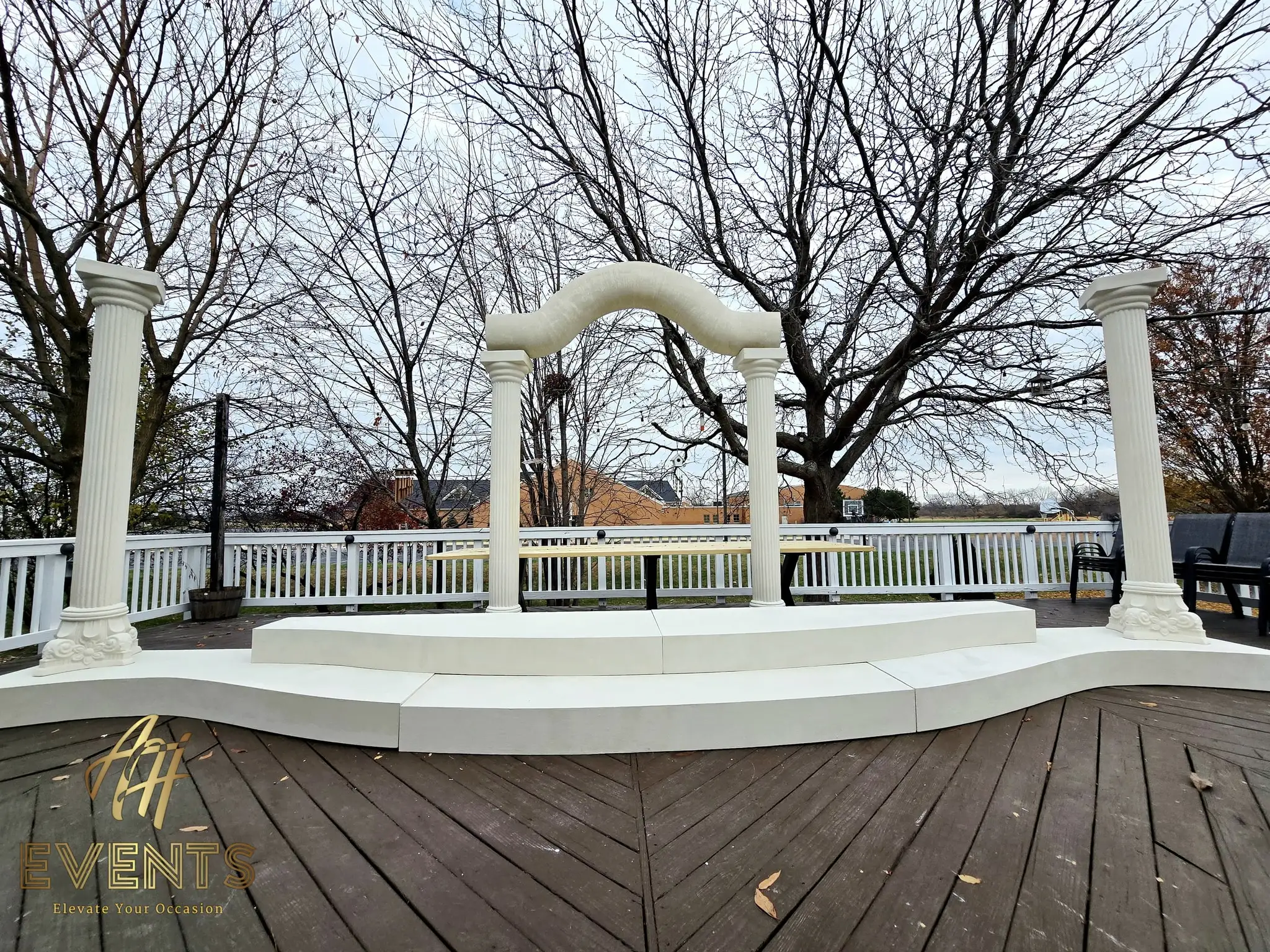 Finished classical-pillar stage on a deck — two fluted columns carrying a serpentine arch above a curved white step base