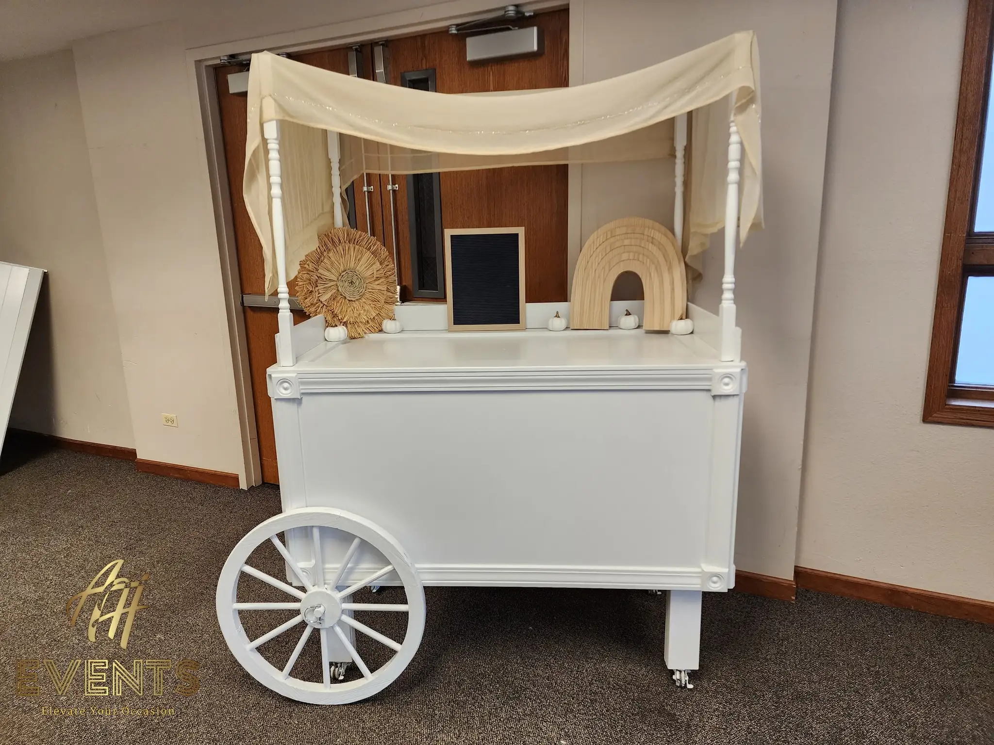 White canopy cart styled with a pampas sunburst and a wooden rainbow for a boho shower
