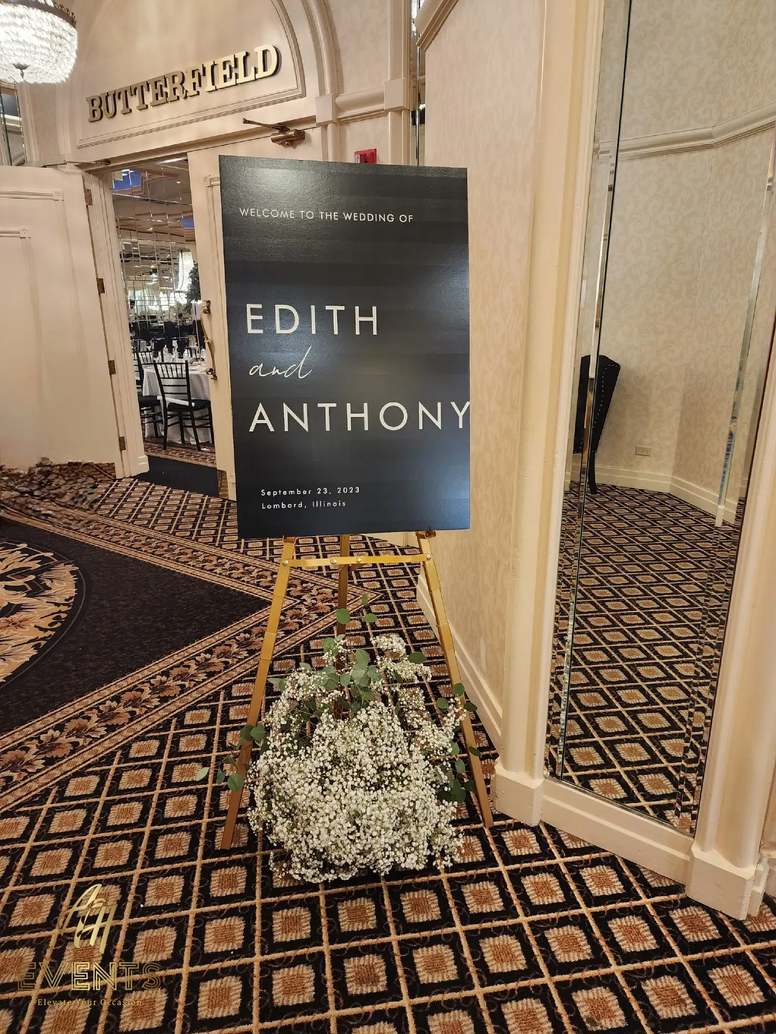 Welcome easel sign reading 'Edith and Anthony, September 23, 2023' with baby's breath at the ballroom entrance