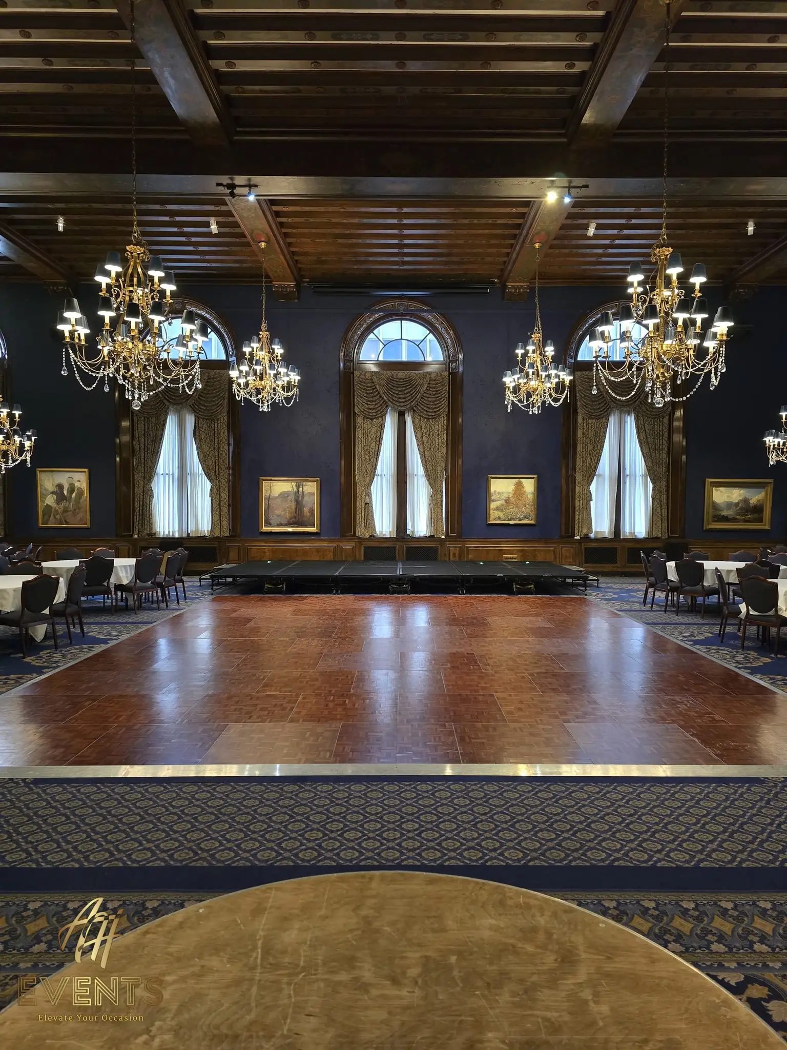 Polished parquet wood dance floor in the wood-beamed ballroom with crystal chandeliers and arched windows