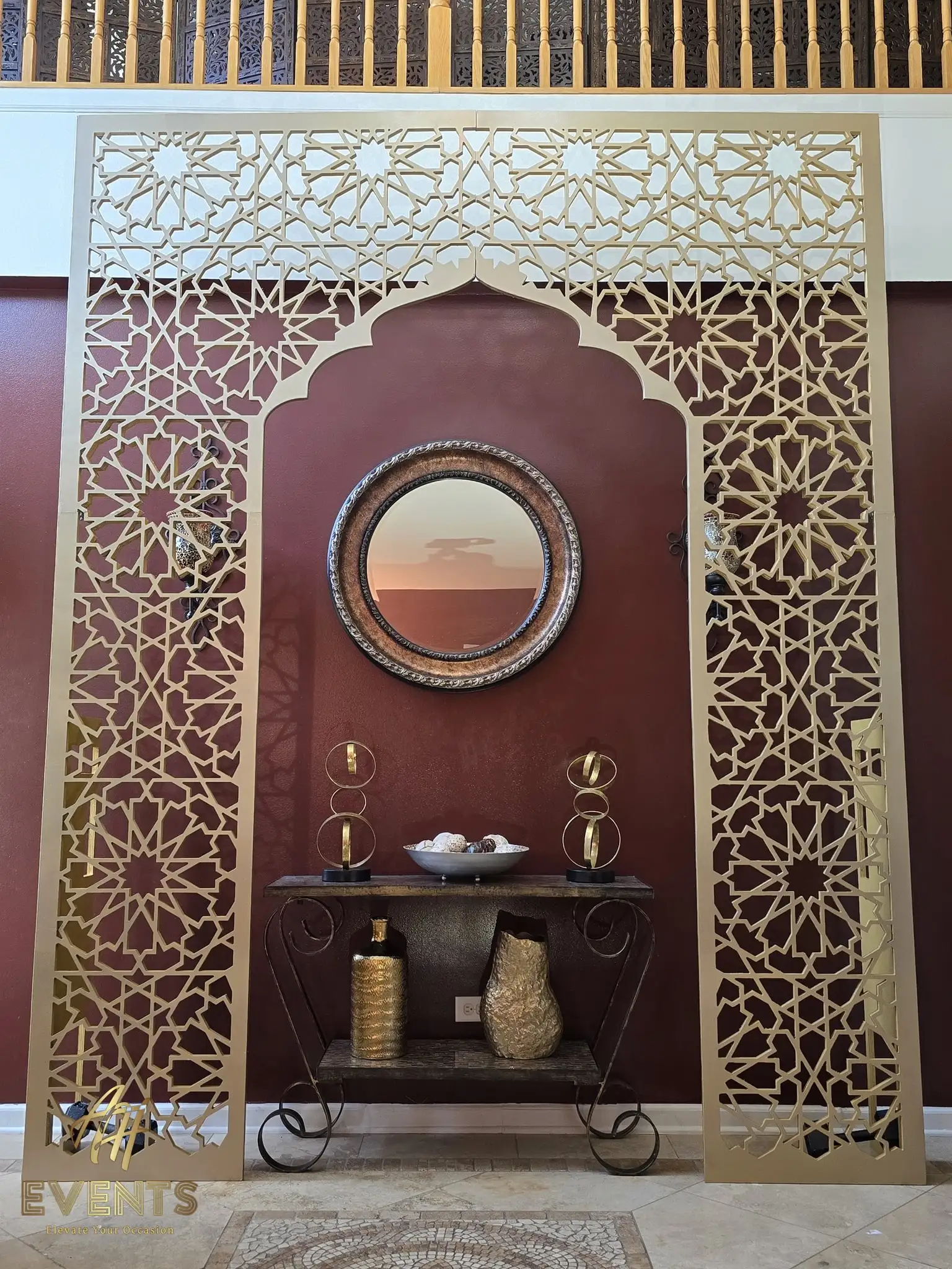 Champagne-gold matrix arch in a foyer, showing the geometric star-lattice cut and pointed Mughal opening