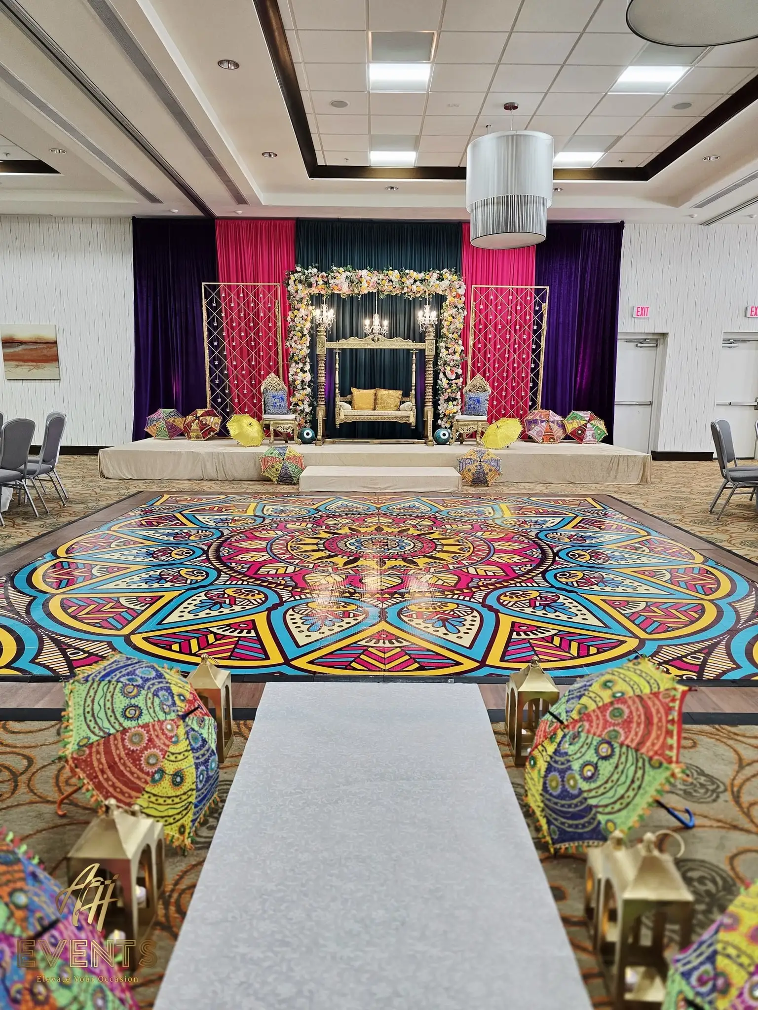 Mandala dance floor before a magenta-and-gold draped stage with a swing seat, a white aisle leading in