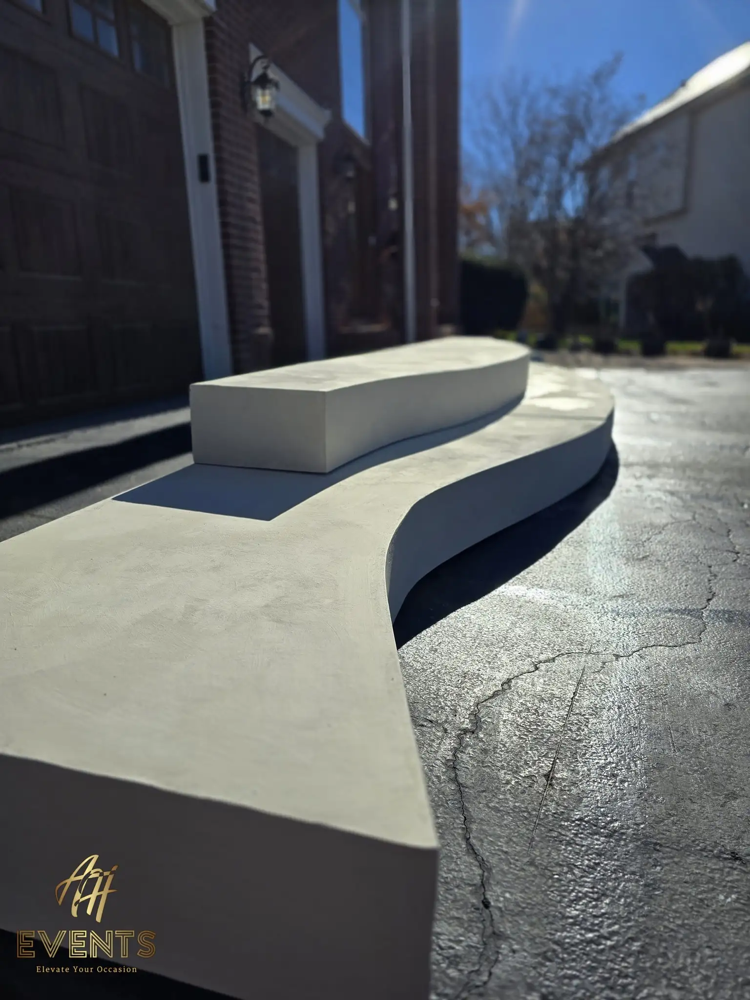 S-curved contoured stage platform freshly plastered white, viewed along its serpentine front edge in a driveway