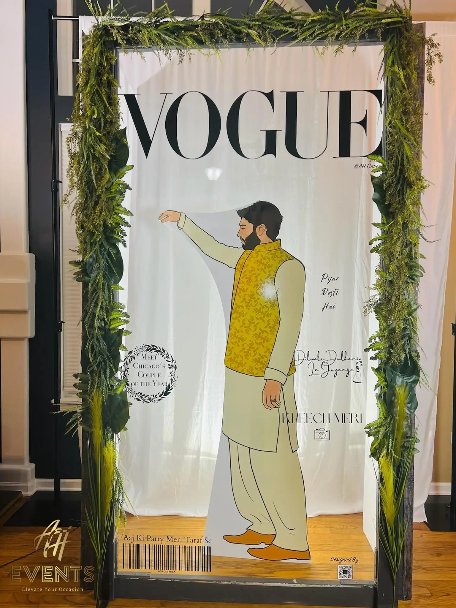 VOGUE-style photo-booth frame with an illustrated groom, draped in greenery and marigold garlands