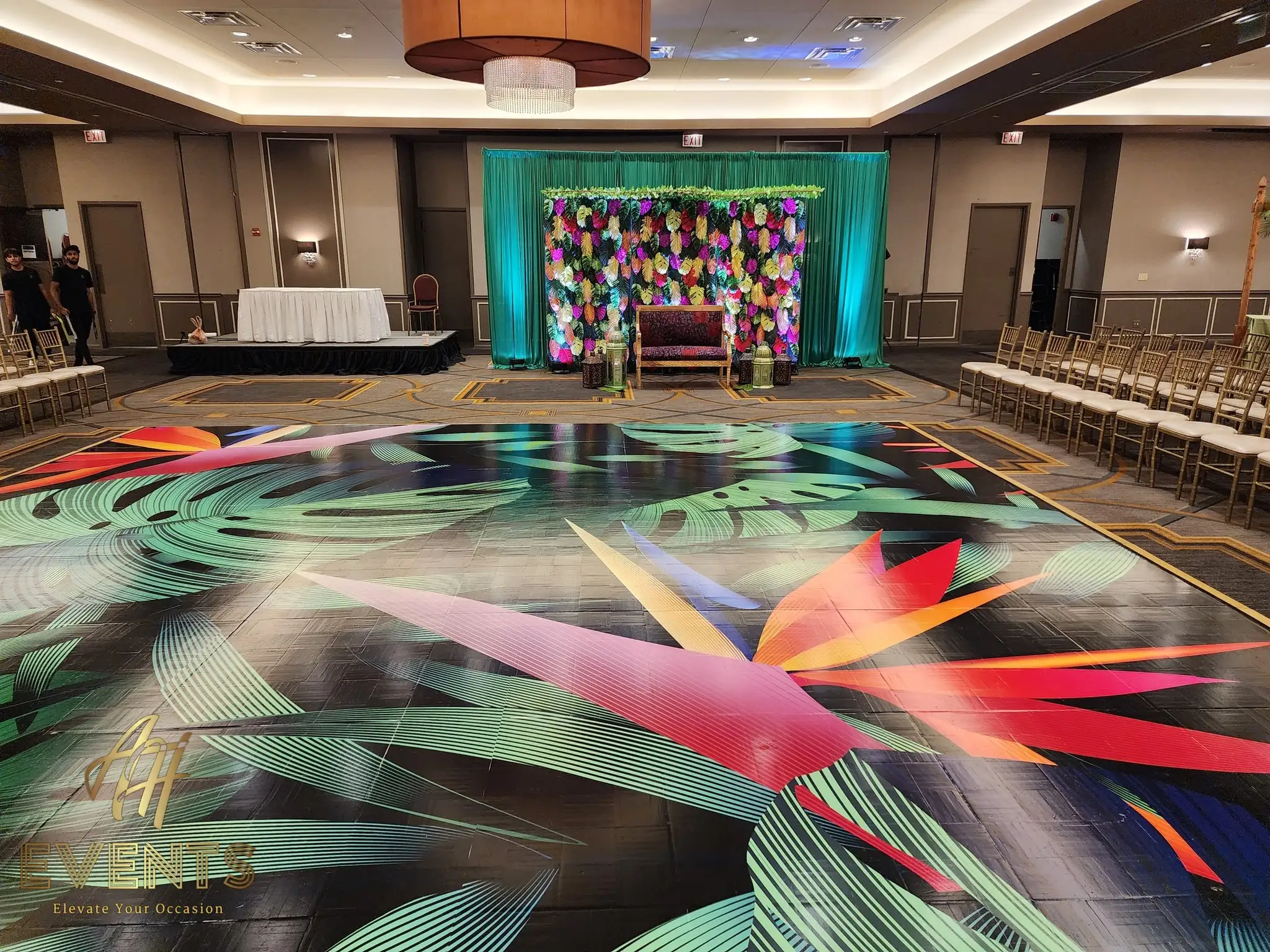 Tropical leaf-art dance floor on black, angled view toward the teal floral stage