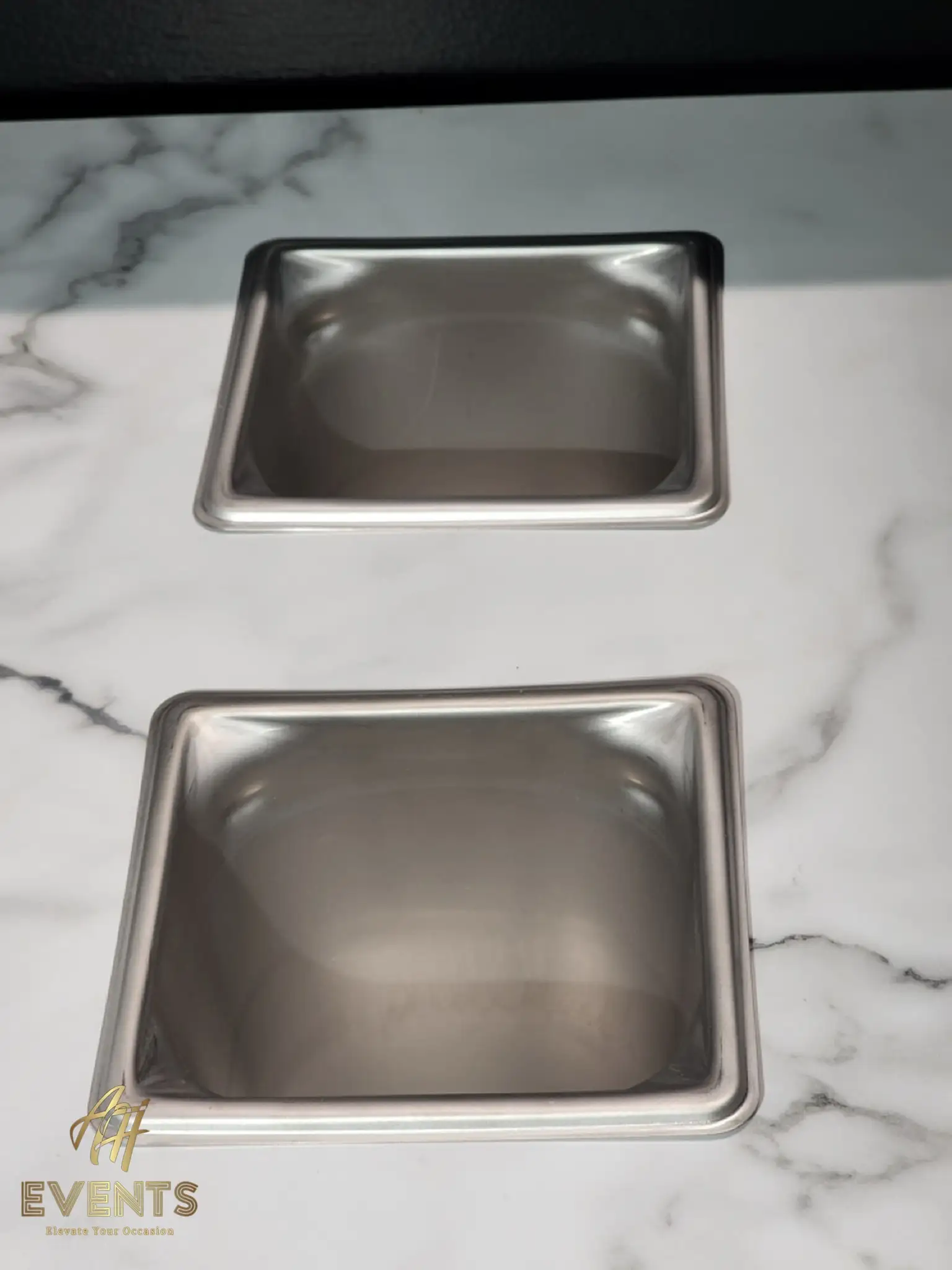 Close view of two stainless inset pans in the white marble countertop of the Bobawala cart