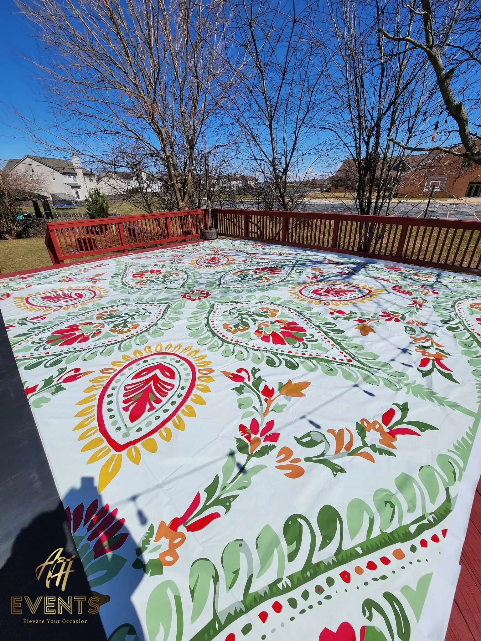 Paisley-patterned flex vinyl floor on a backyard wooden deck, photographed at an angle with bare winter trees behind