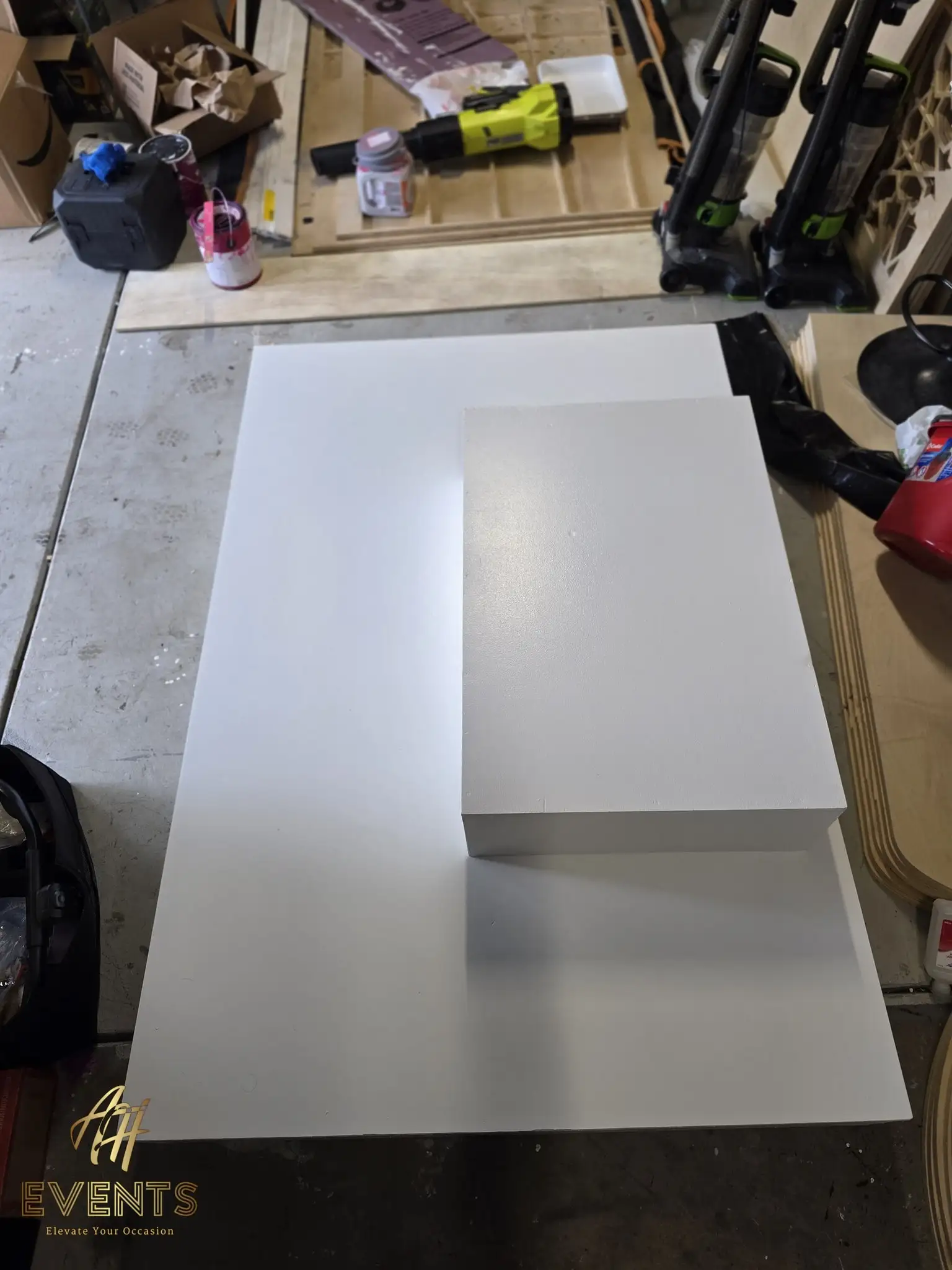 White notched stage platform with a riser block on a workshop table during the build