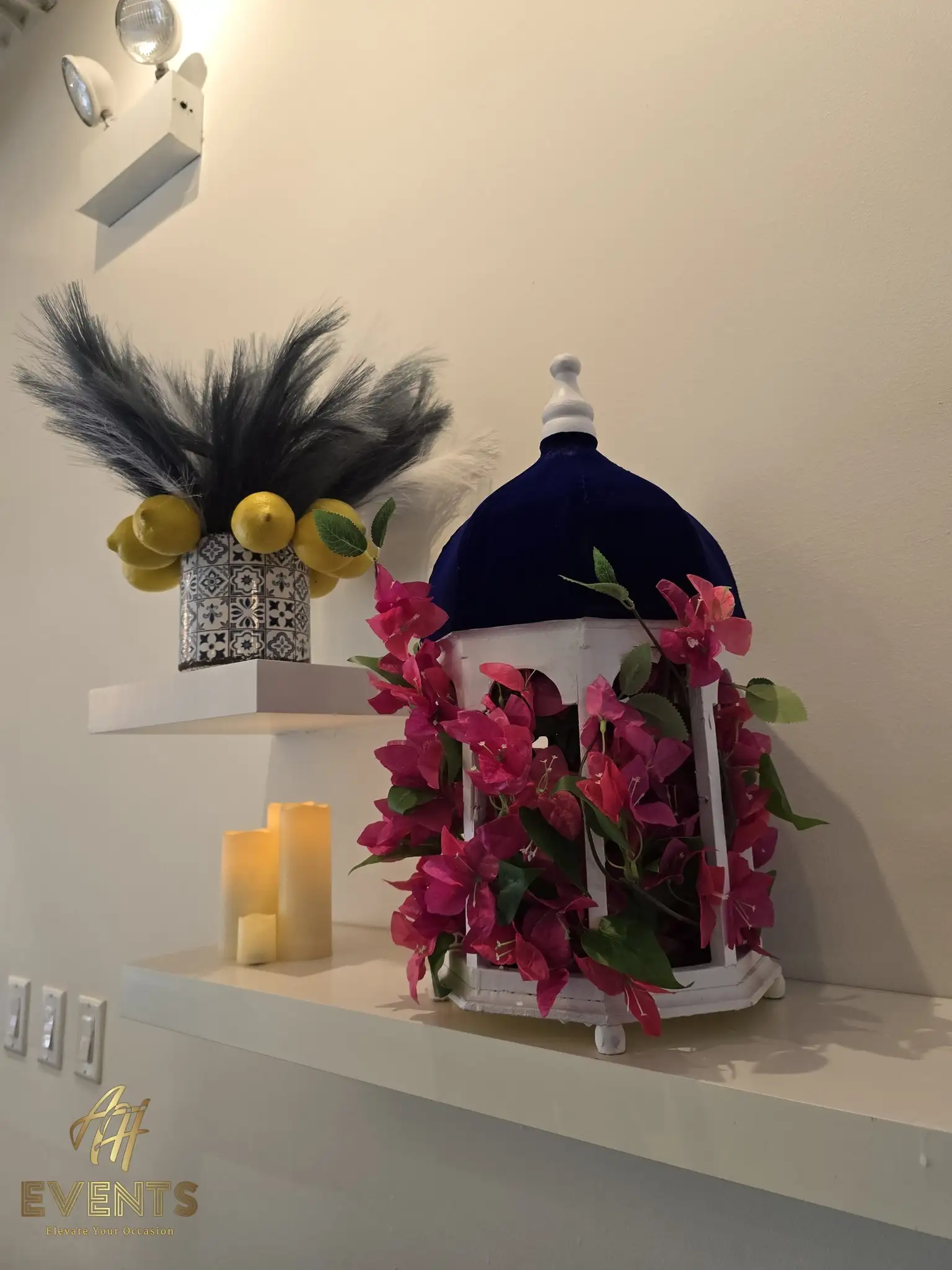 Decor vignette on floating shelves — a white lantern with magenta bougainvillea beside a tiled vase topped with lemons and pampas