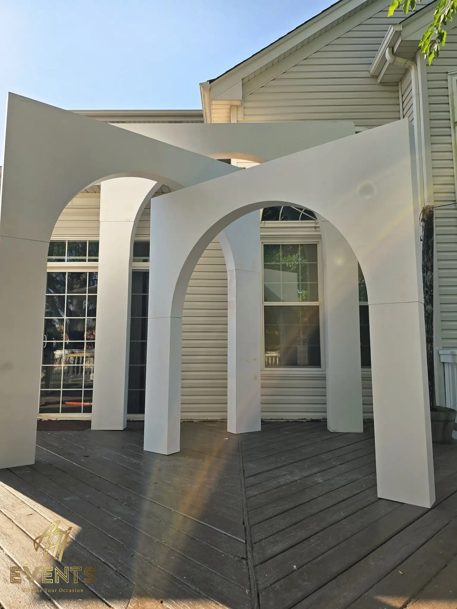 Nested white arches of graduated depth on a deck, angled view with sun flare