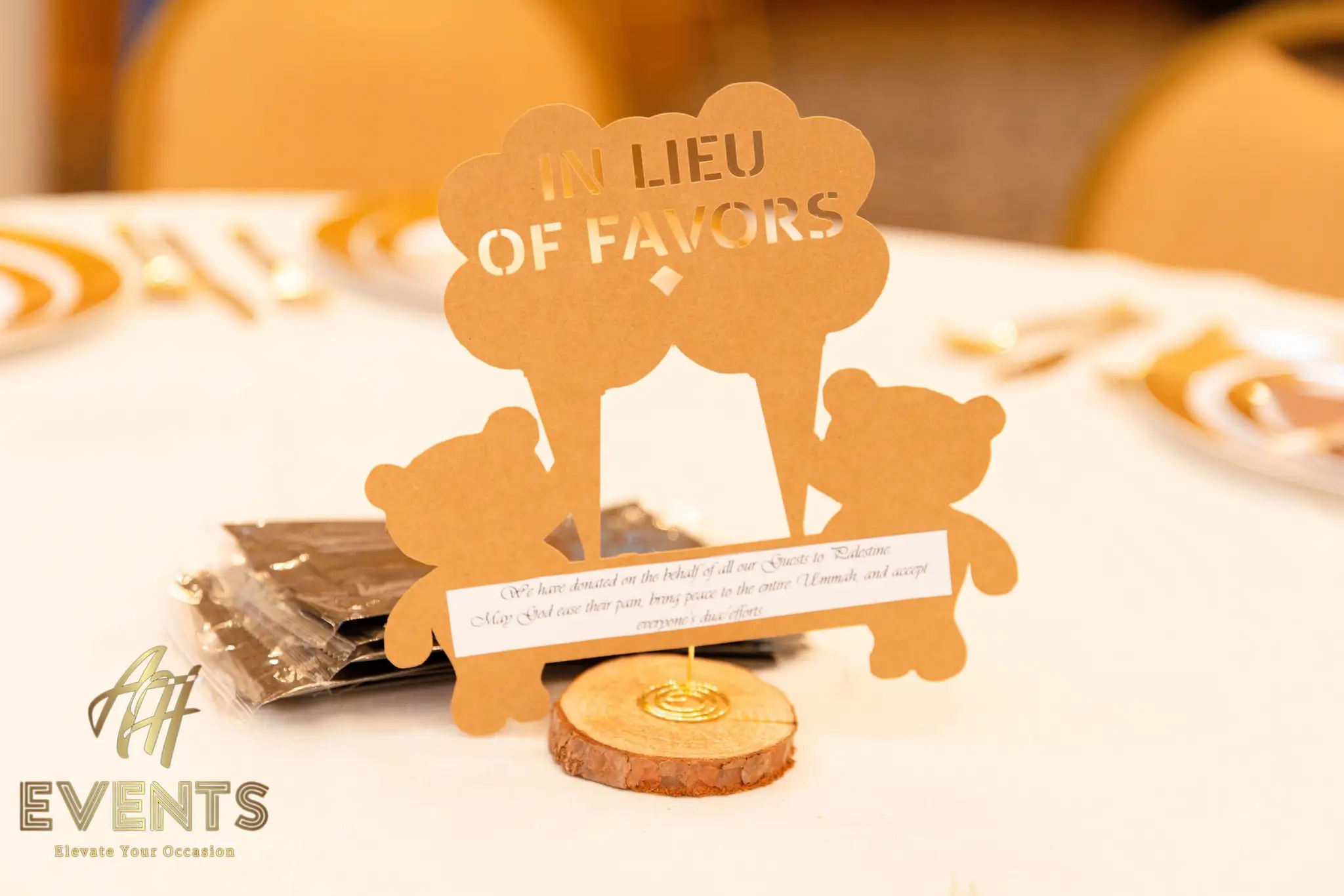 Bear-shaped 'In Lieu of Favors' card noting a charity donation, with chocolate favors at a place setting