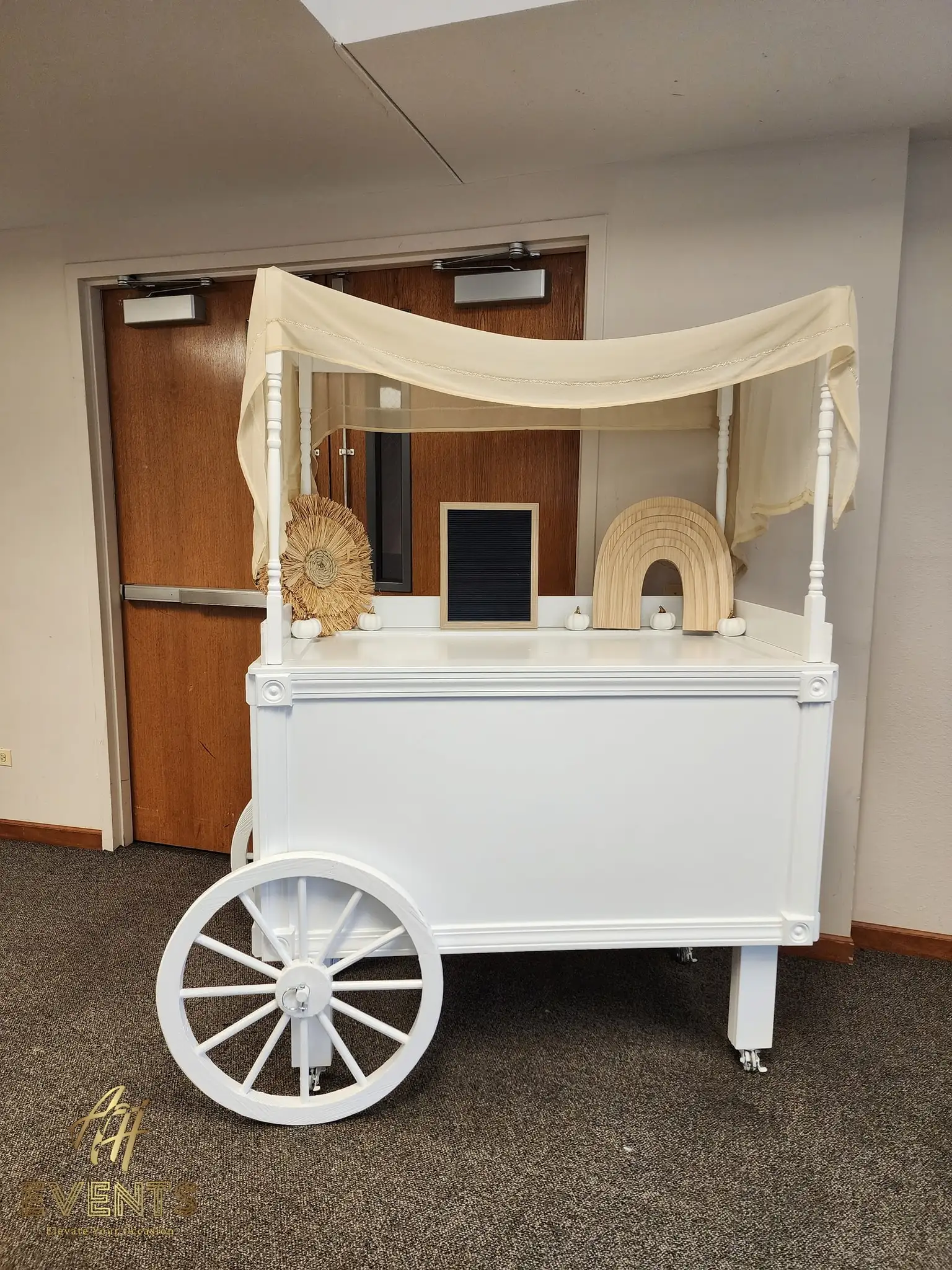 White favor cart with a sheer canopy, a chalkboard sign and a wooden rainbow