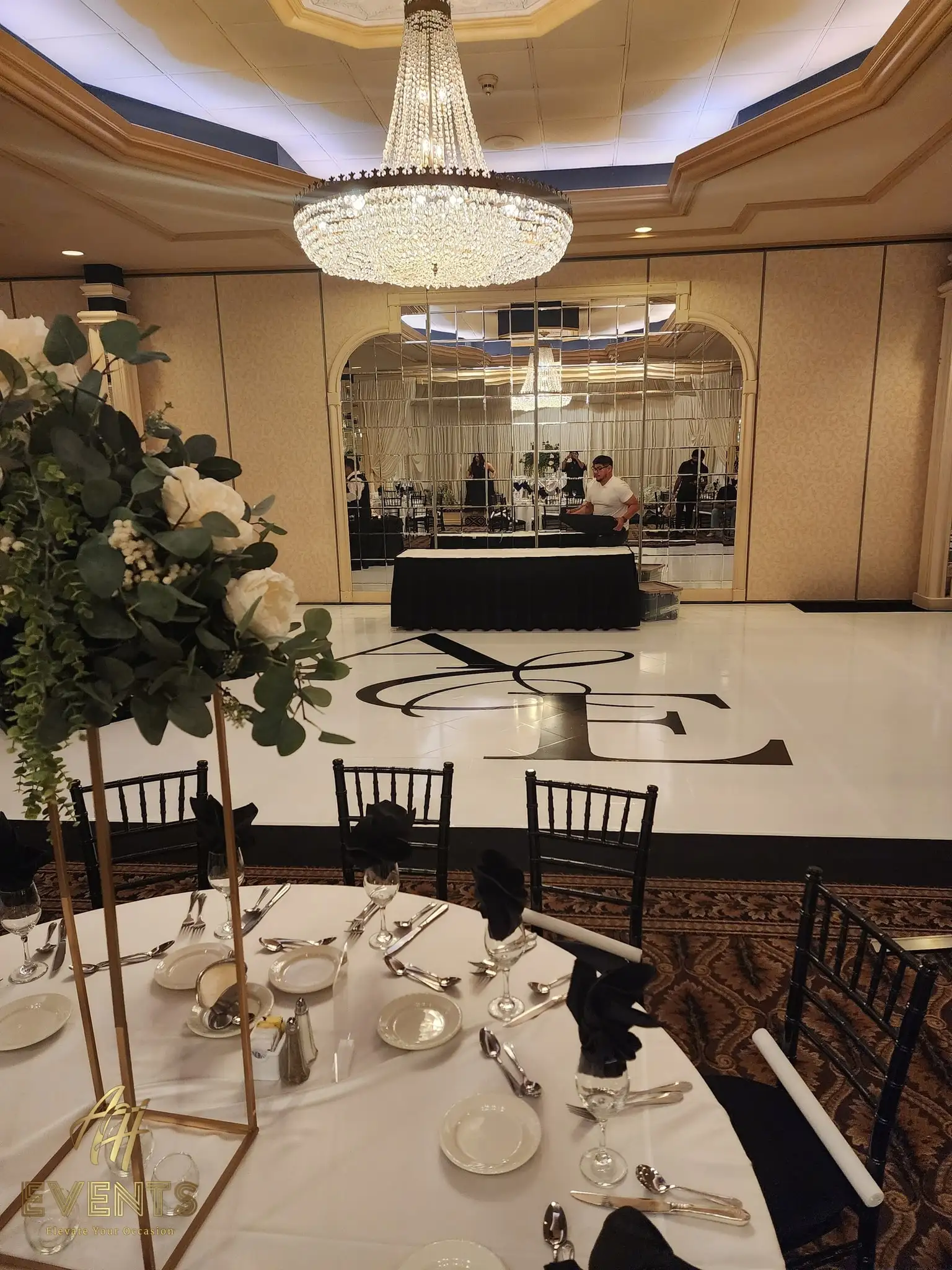 Place setting with black napkins in the foreground, the white 'A&E' monogram floor and mirrored wall behind