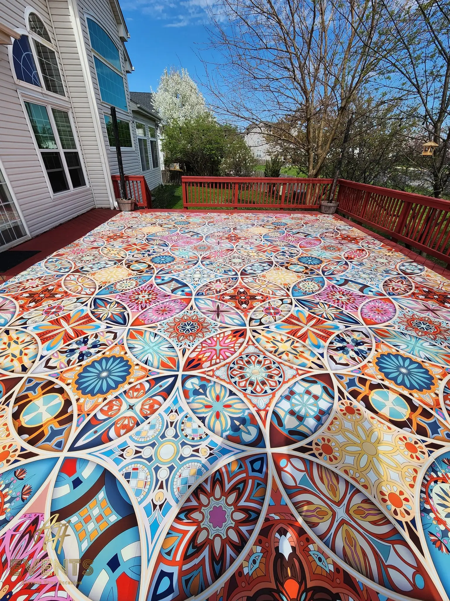 Kaleidoscope floor laid on a backyard deck under a clear blue sky, beside a house
