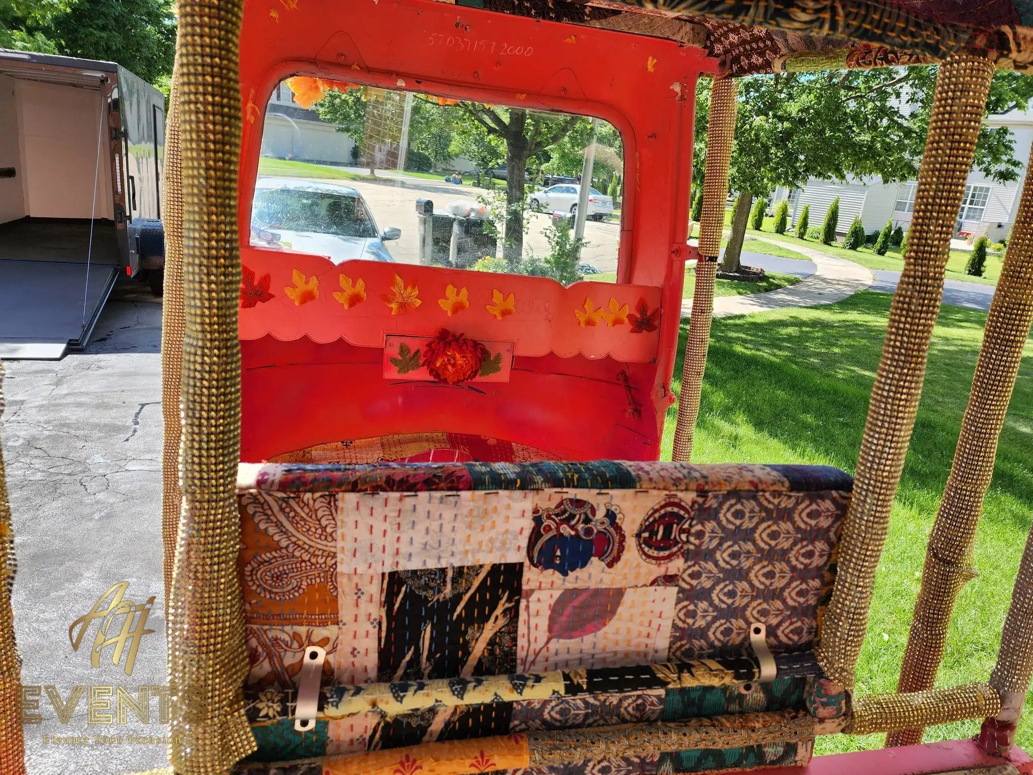 Rear interior of the auto rickshaw with a red-framed window and patchwork bench seat