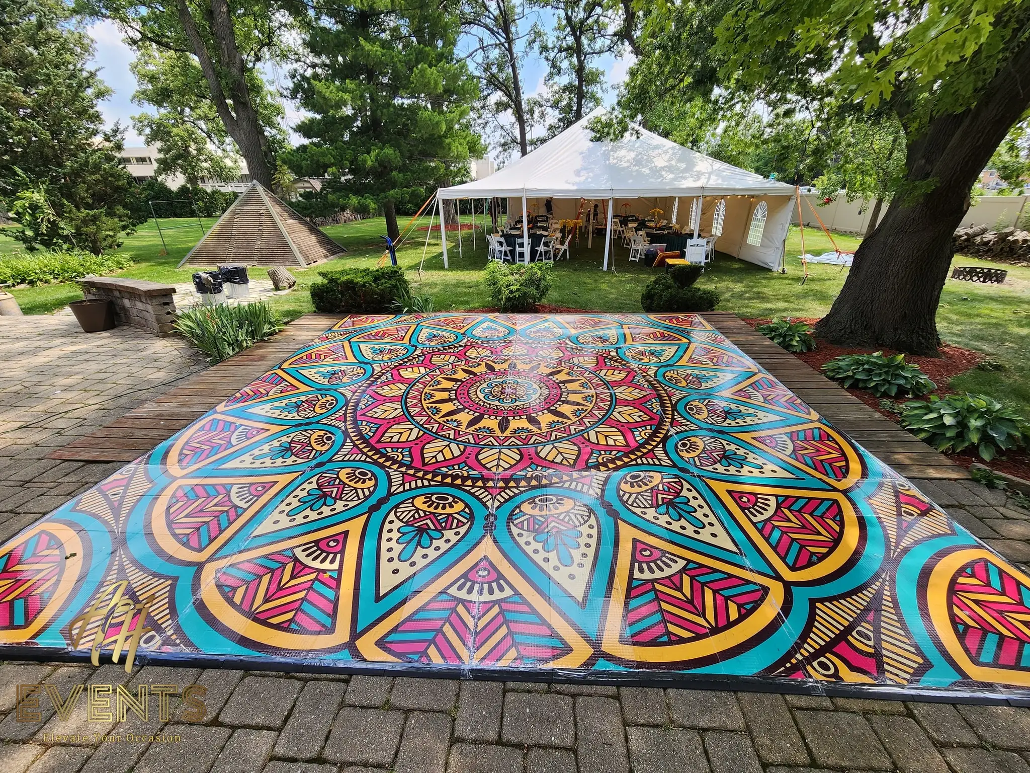 Mandala floor on a brick patio with a white event tent behind