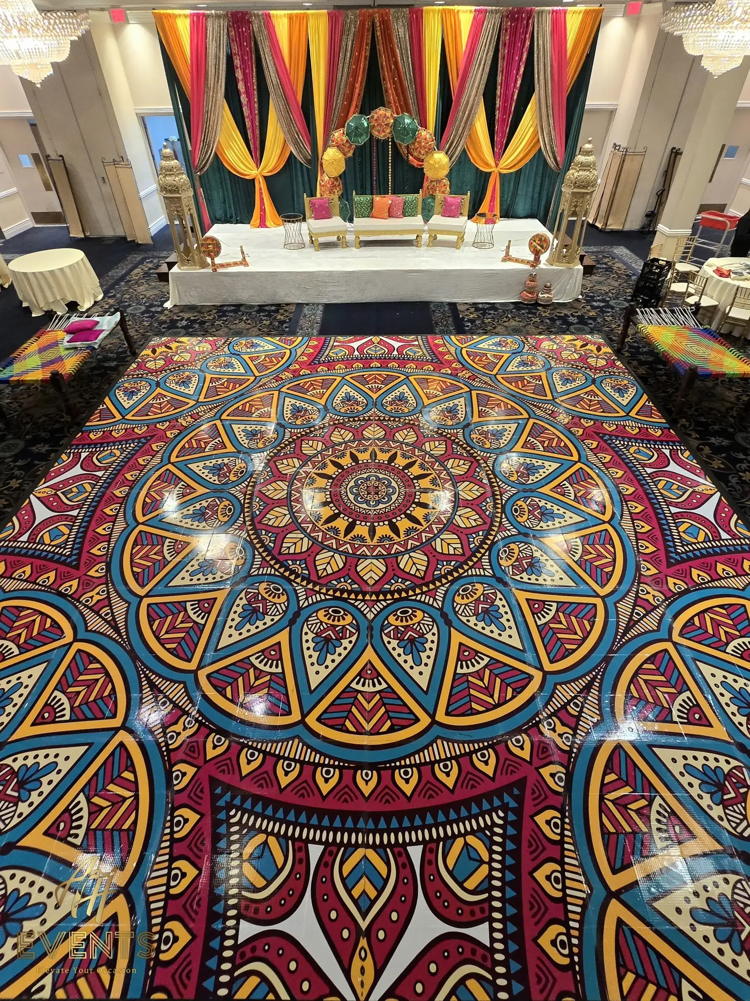 Angled view of the mandala floor leading to a colorful striped-drape wedding stage