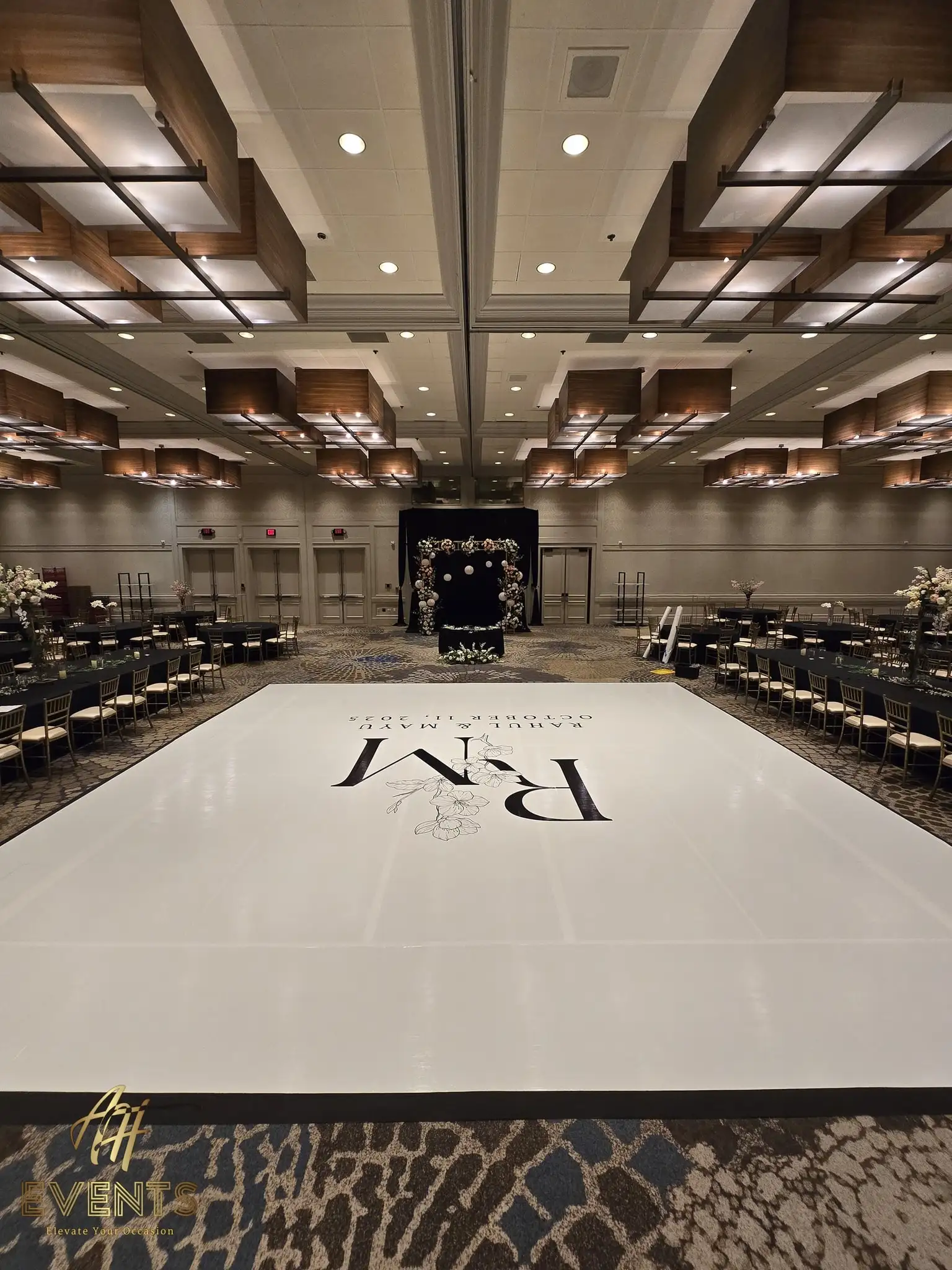 Vertical view of the white 'R M' monogram dance floor leading to the black lattice mandap stage