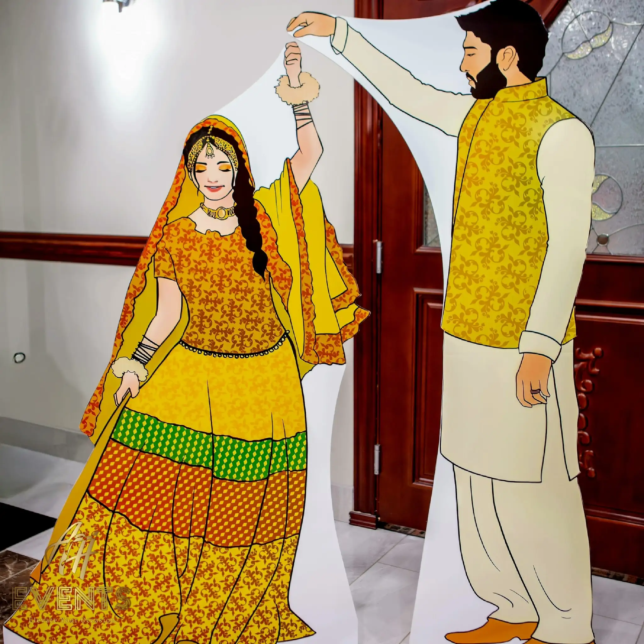 Life-size illustrated cutout of a couple in yellow Mehndi attire used as an event photo prop