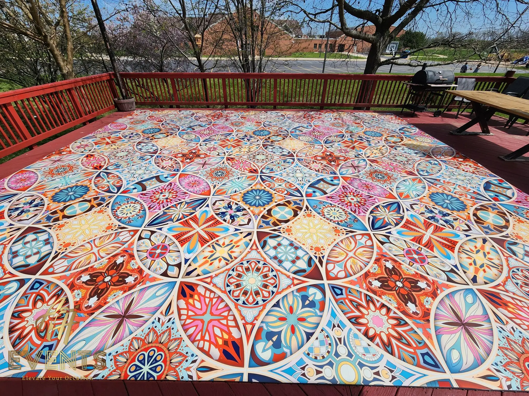 Kaleidoscope decorative floor on an outdoor deck with a red railing, photographed in daylight