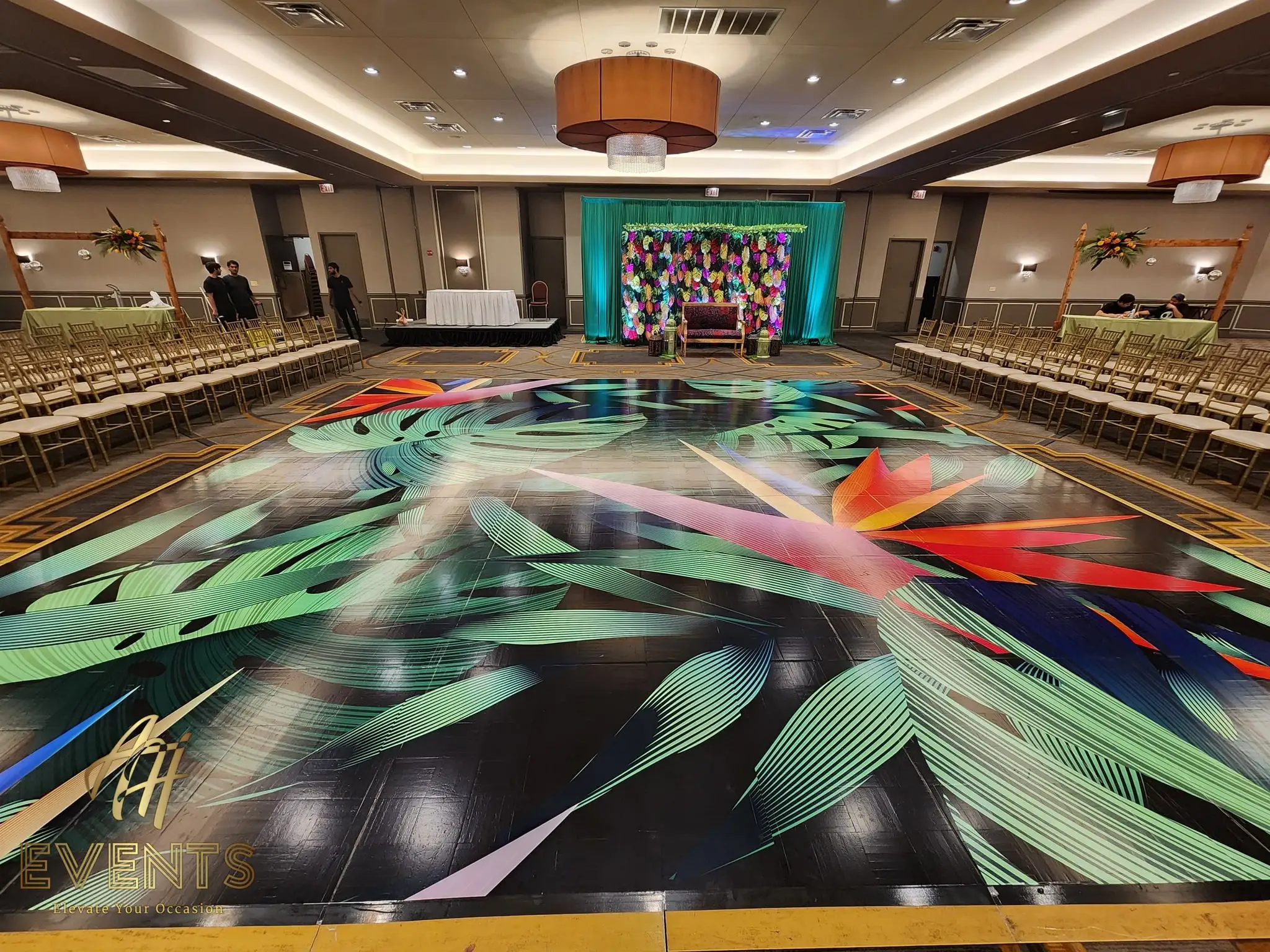 Tropical leaf-art floor showing a bird-of-paradise burst, the teal floral stage behind