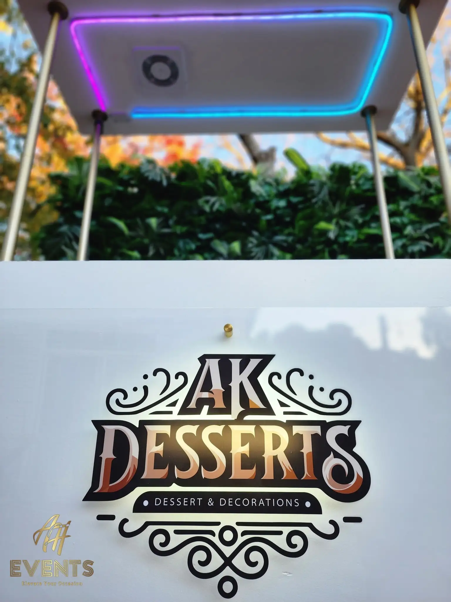 AK Desserts cart canopy lit with pink-and-blue LED edge lighting and a spotlight, above the backlit logo panel