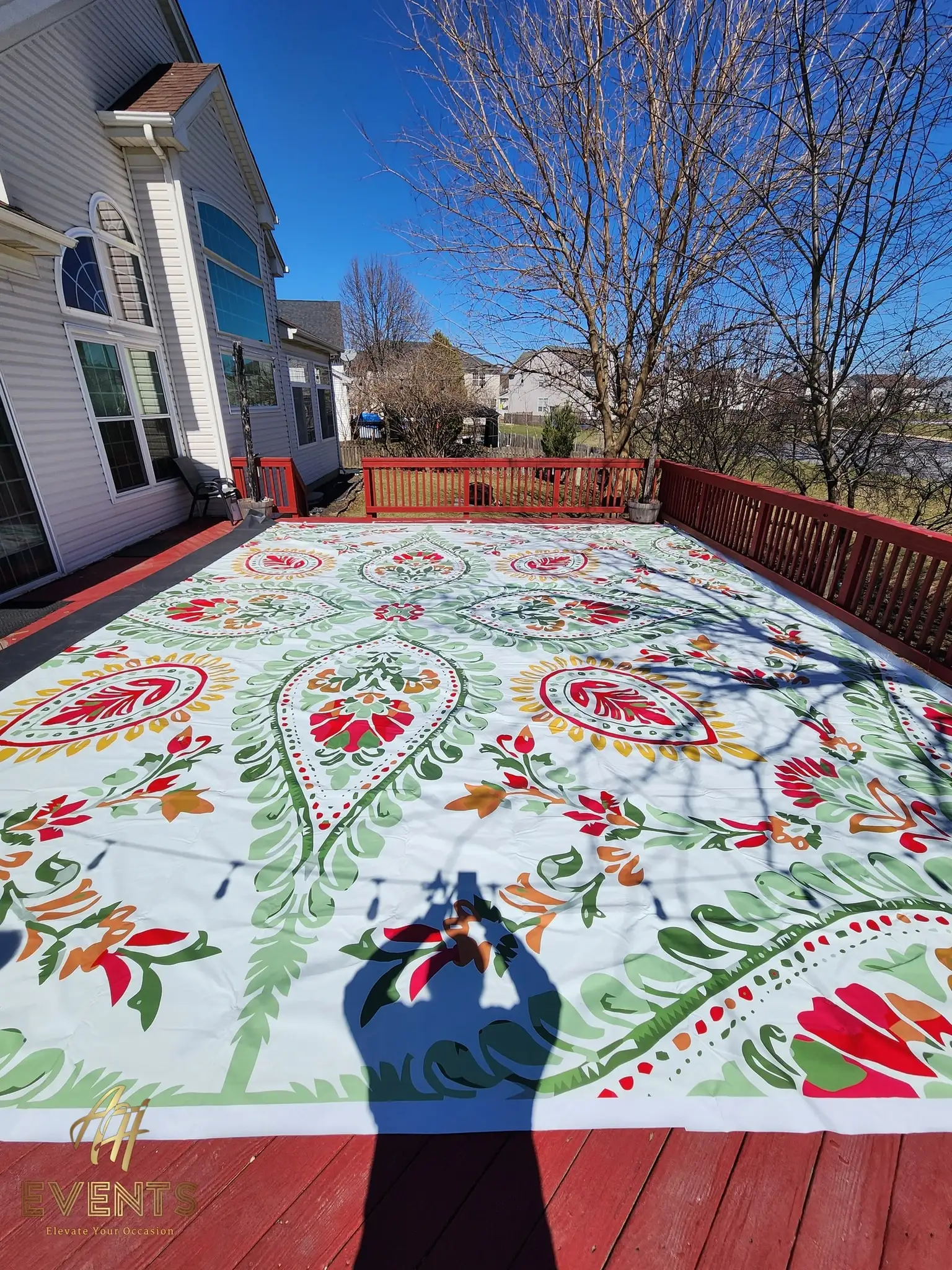 Paisley flex vinyl floor on a backyard deck beside a house, bordered by a red wooden railing
