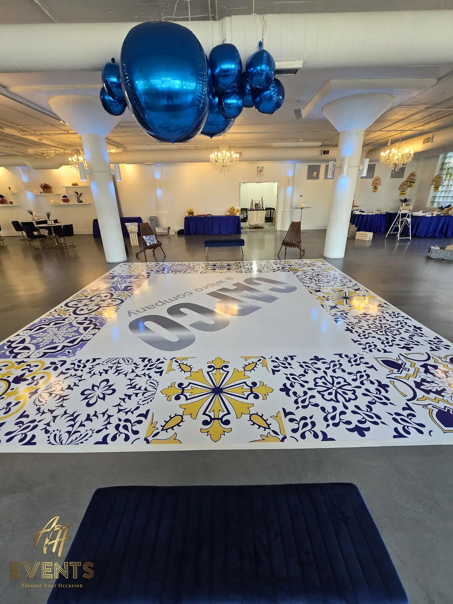 CAPCO tiled dance floor among loft columns with blue balloon clusters above