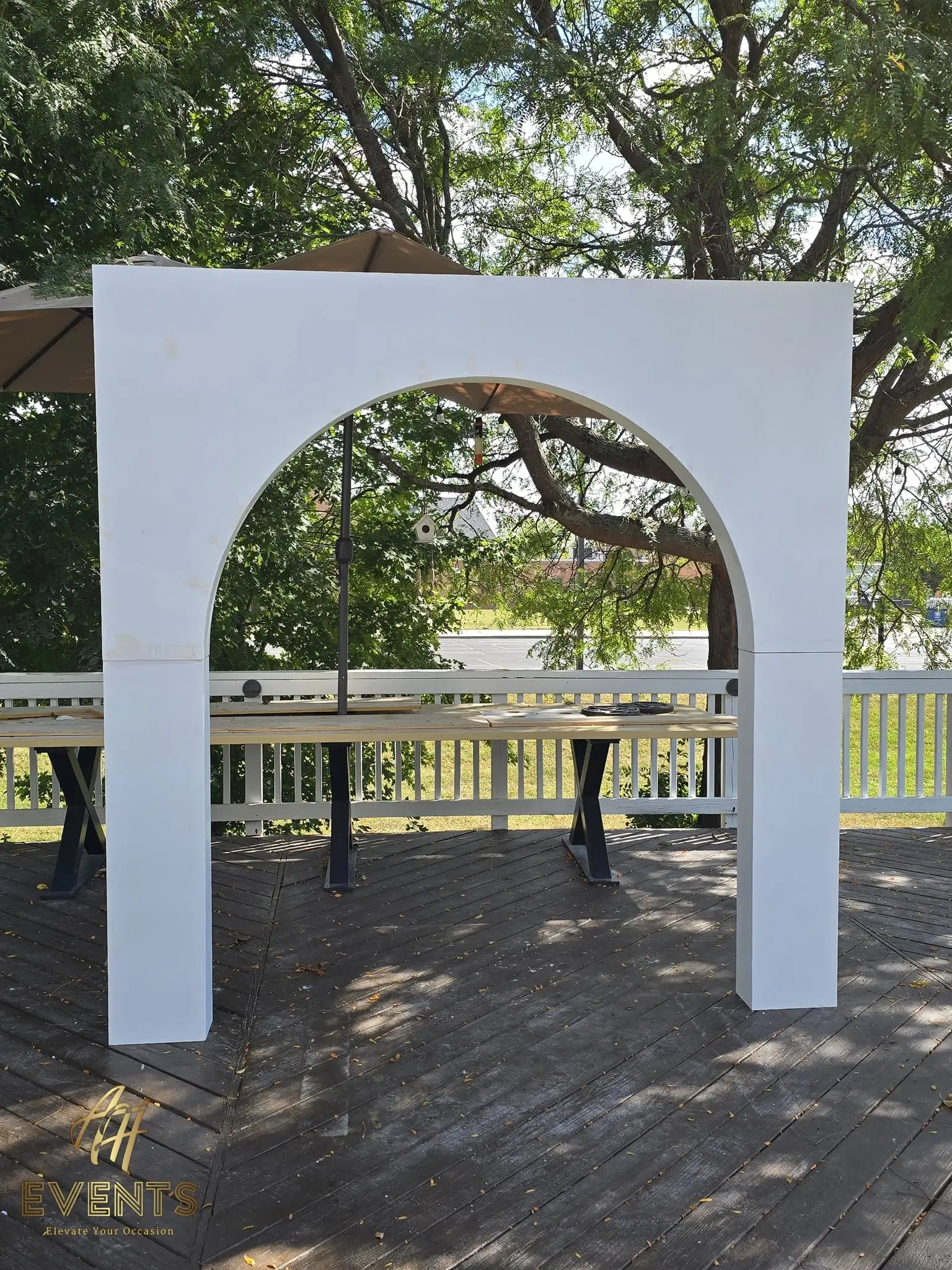 Single white square-framed arch with a rounded opening on a deck among trees