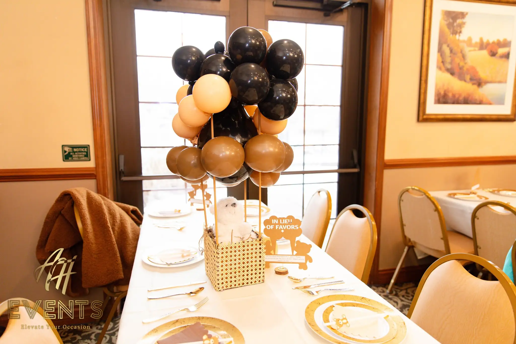 Banquet table with a hot-air-balloon centerpiece and gold chargers at the bear-themed baby shower