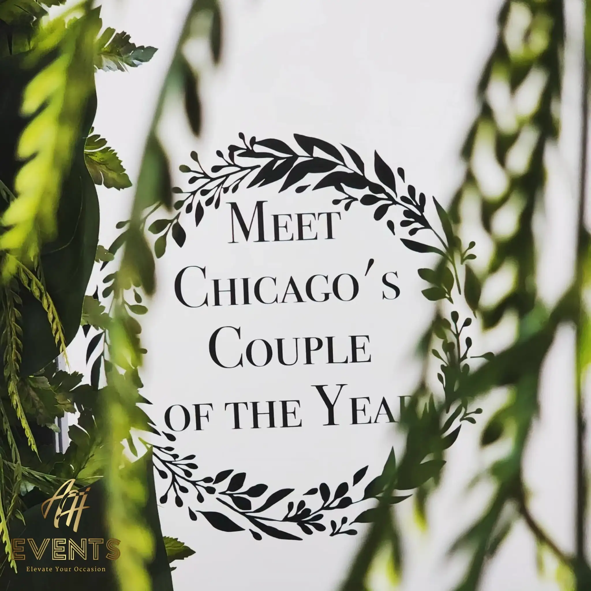 'Meet Chicago's Couple of the Year' photo-booth sign within a leafy wreath and hanging greenery