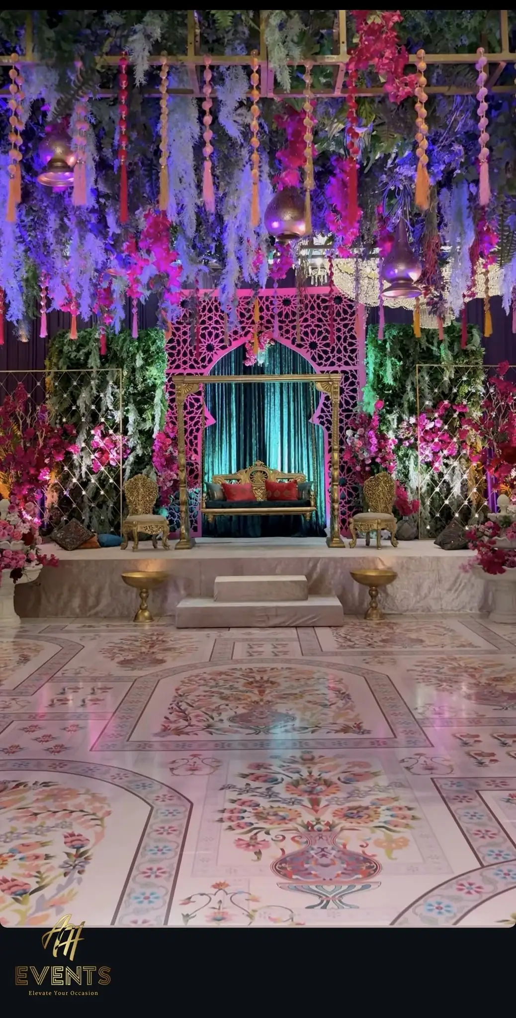 Pink matrix arch on a wedding stage framed by cascading florals and teal drapes