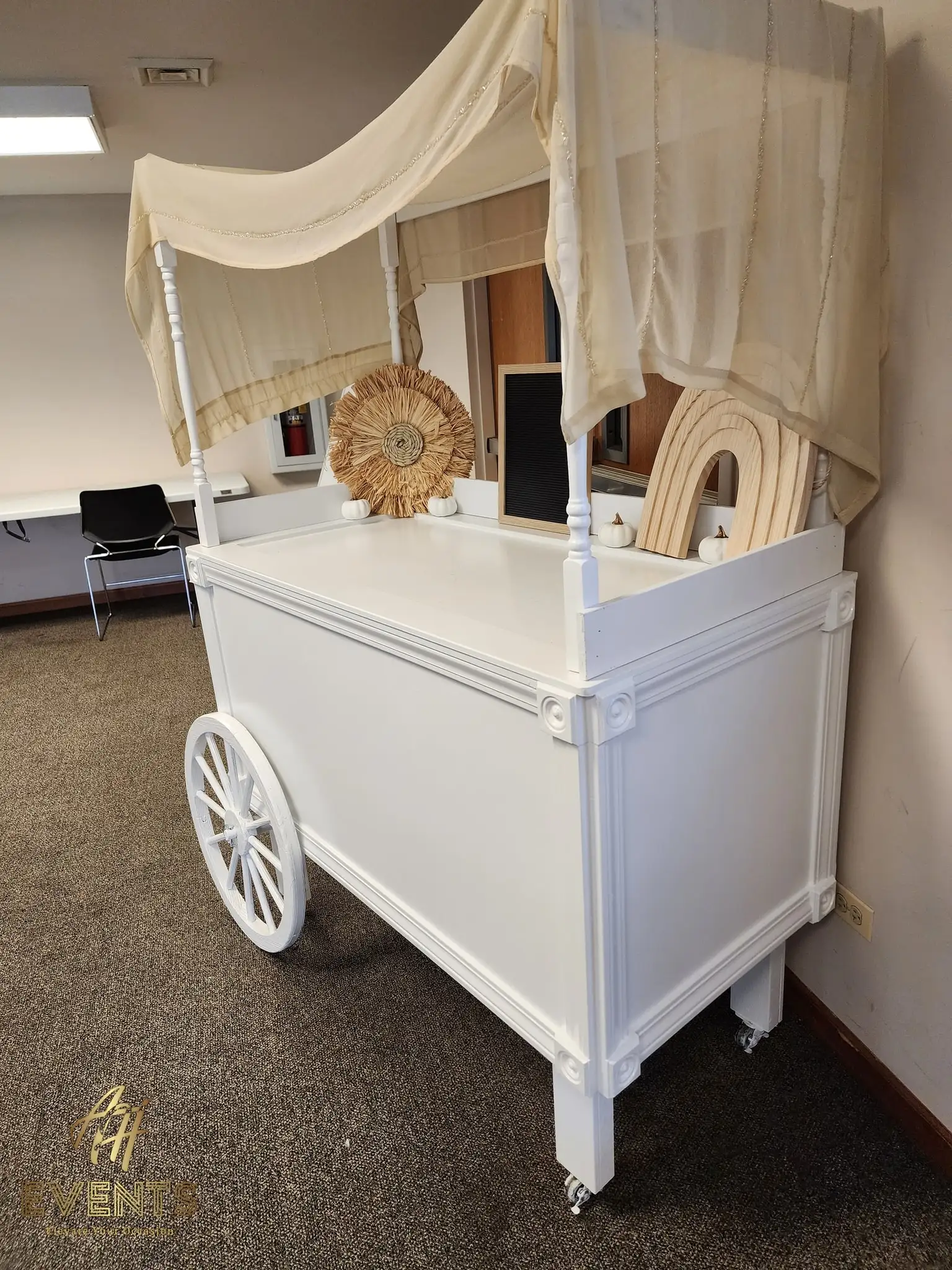 Side view of the white canopy favor cart with a rattan sunburst and rainbow decor