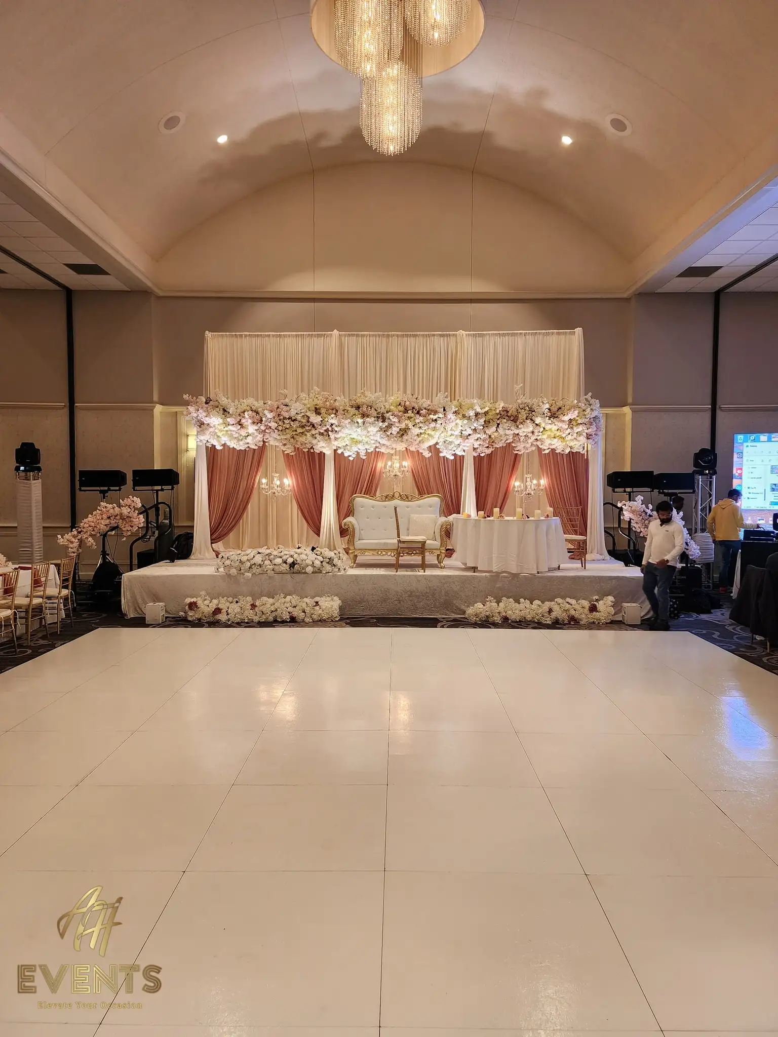 White dance floor facing a blush floral stage with mauve drapes and a tufted loveseat