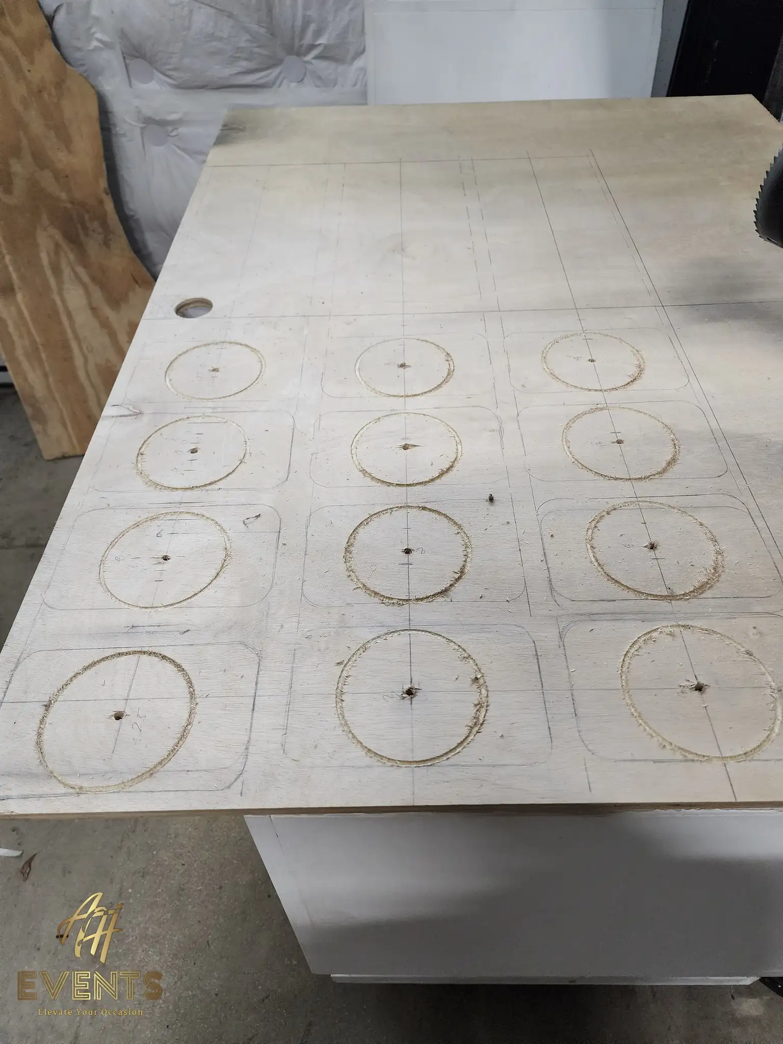 Plywood cart top marked with a grid and circles, several circular cup-hole grooves started with a router