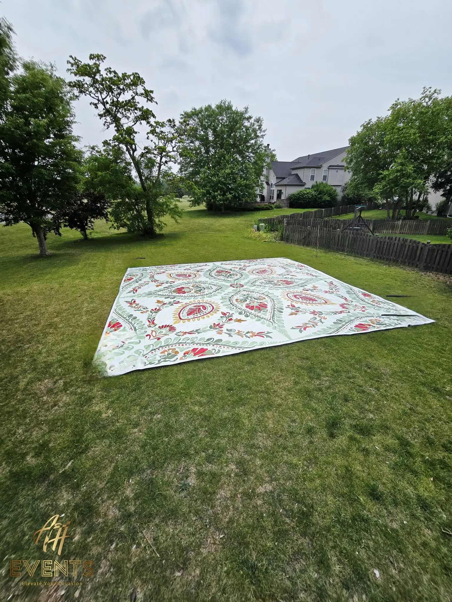 Floral paisley flex vinyl floor laid out on a grass lawn outdoors, surrounded by trees and a fence