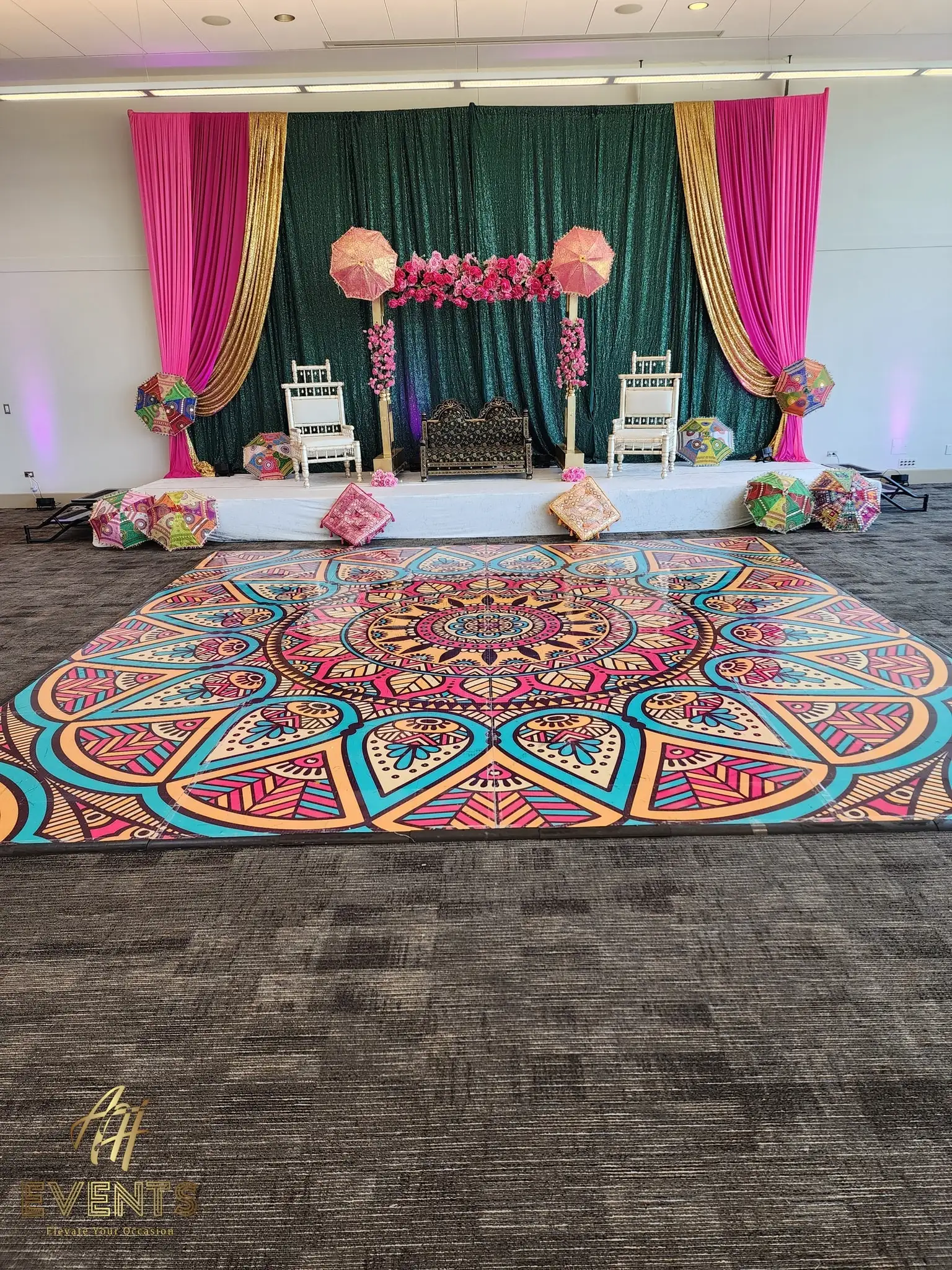 Mandala dance floor in front of a teal-draped stage with peach florals, under lavender uplighting