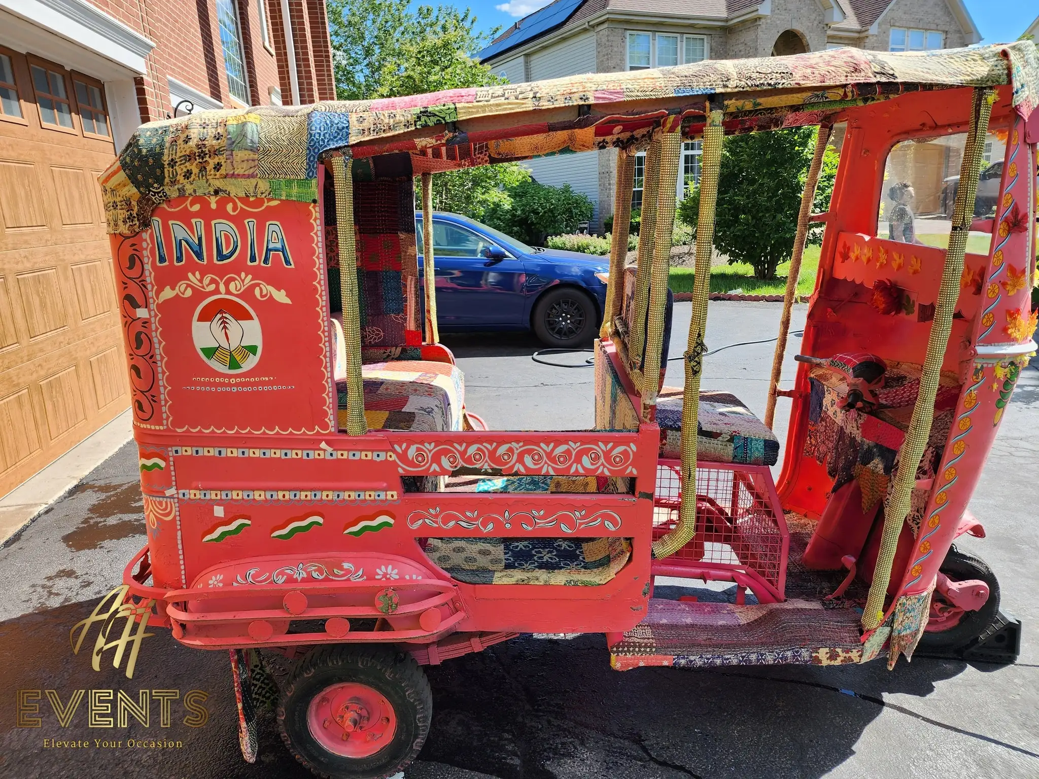 Side of the auto rickshaw showing a hand-painted 'INDIA' panel, patchwork canopy and red bench
