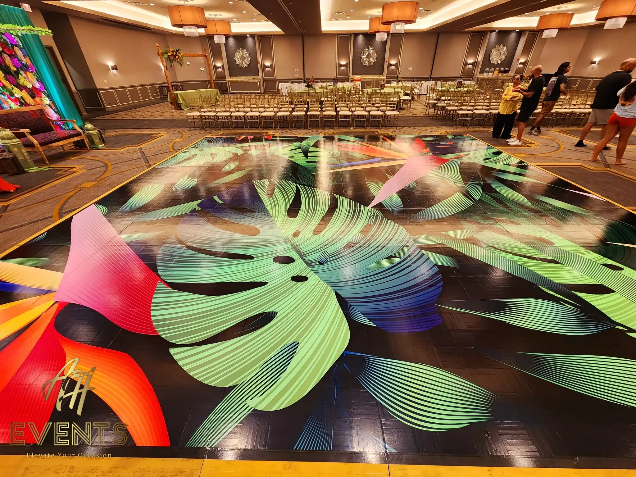 The tropical leaf-art dance floor seen in full, facing the floral stage