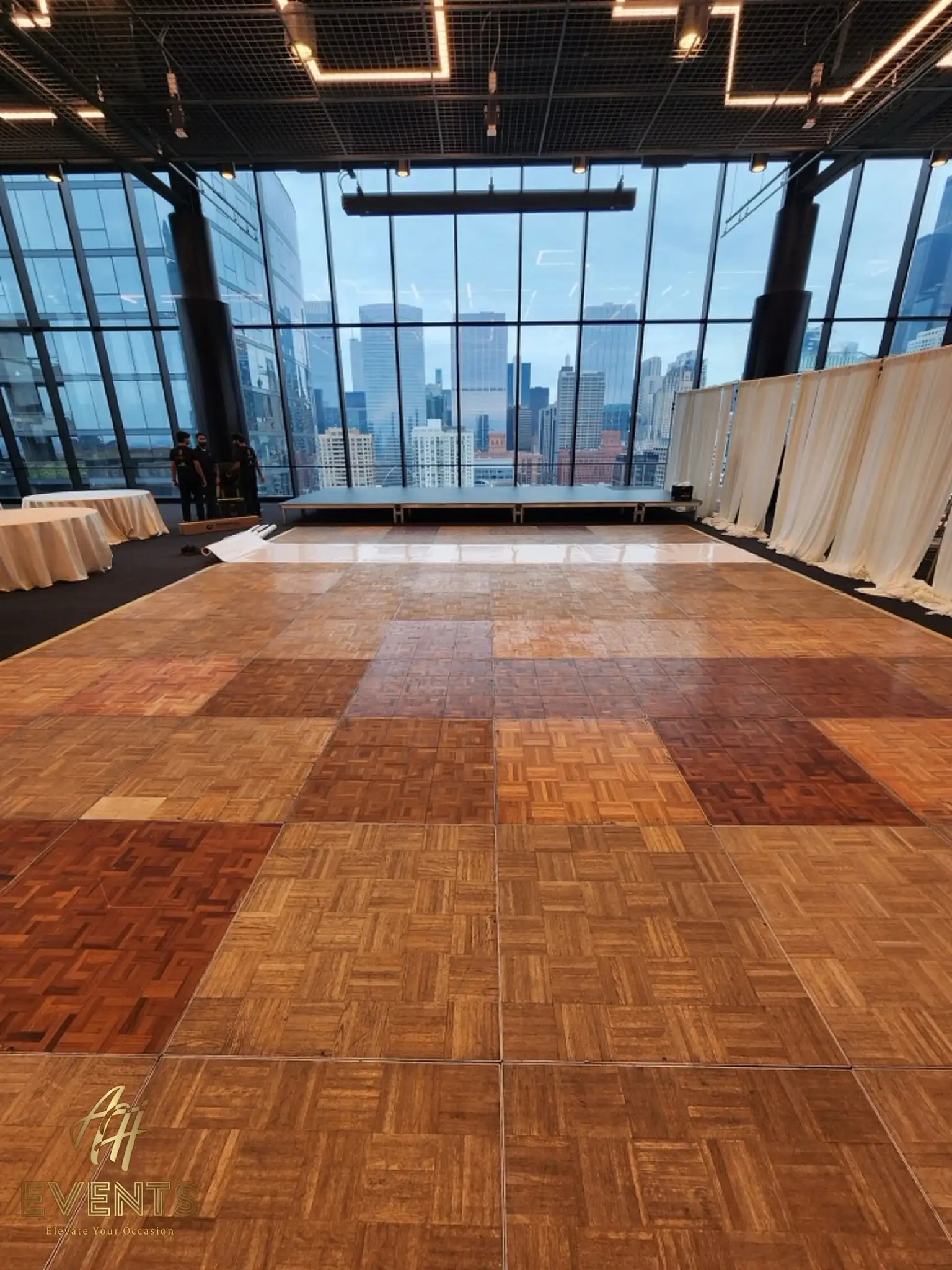 Herringbone wood parquet dance floor in the skyline-windowed loft before setup