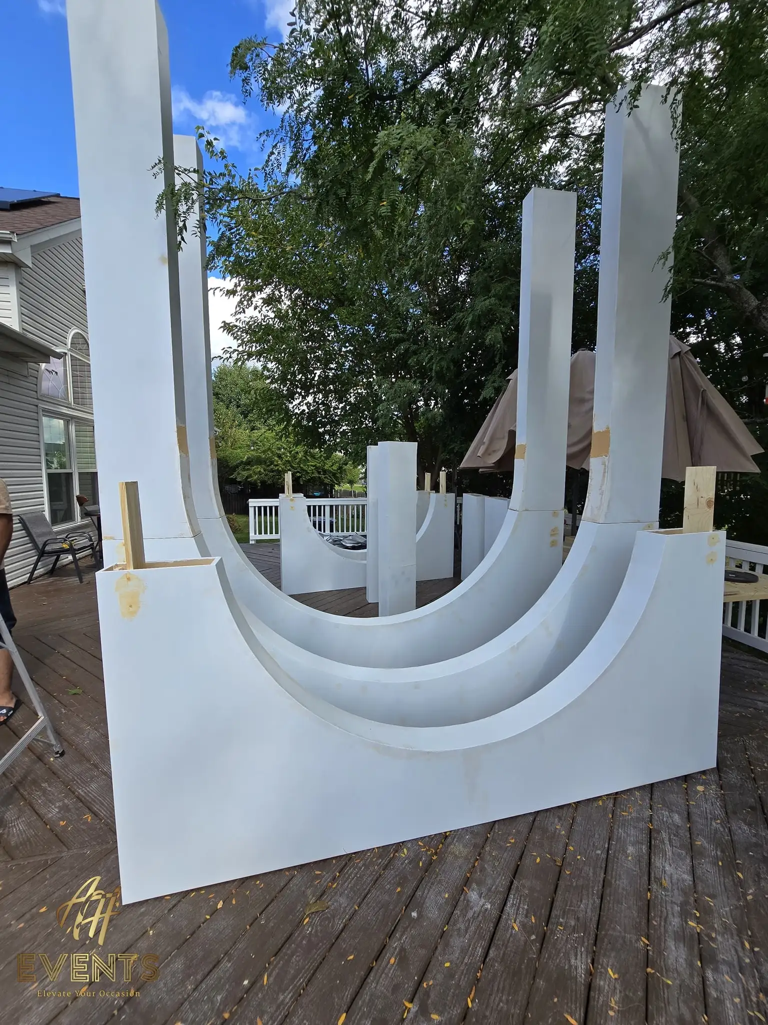 White arch panels laid flat on a deck, showing the stacked curved cut-outs before assembly