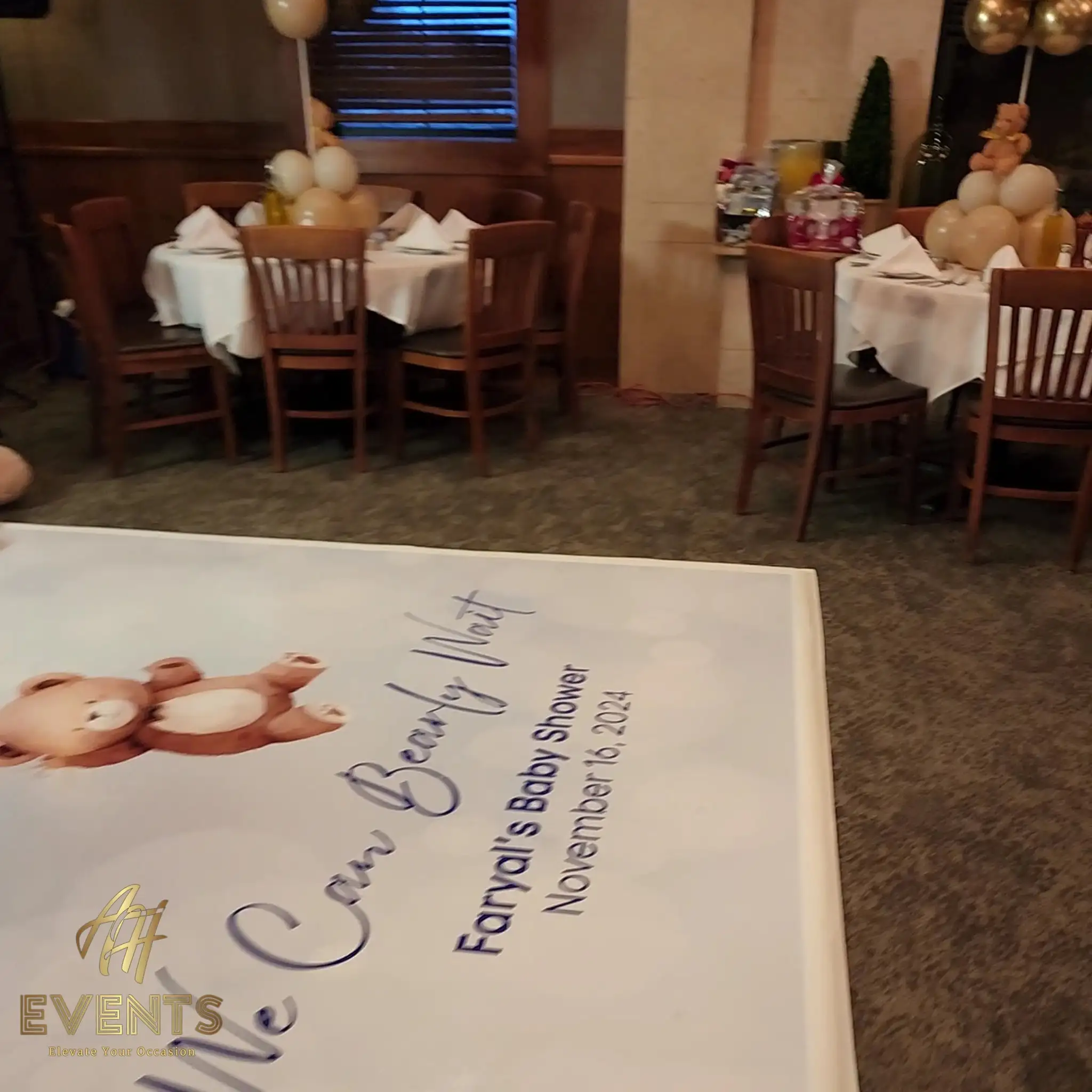 Set banquet tables with teddy-bear centerpieces behind the 'We Can Bearly Wait — Faryal's Baby Shower' printed floor decal