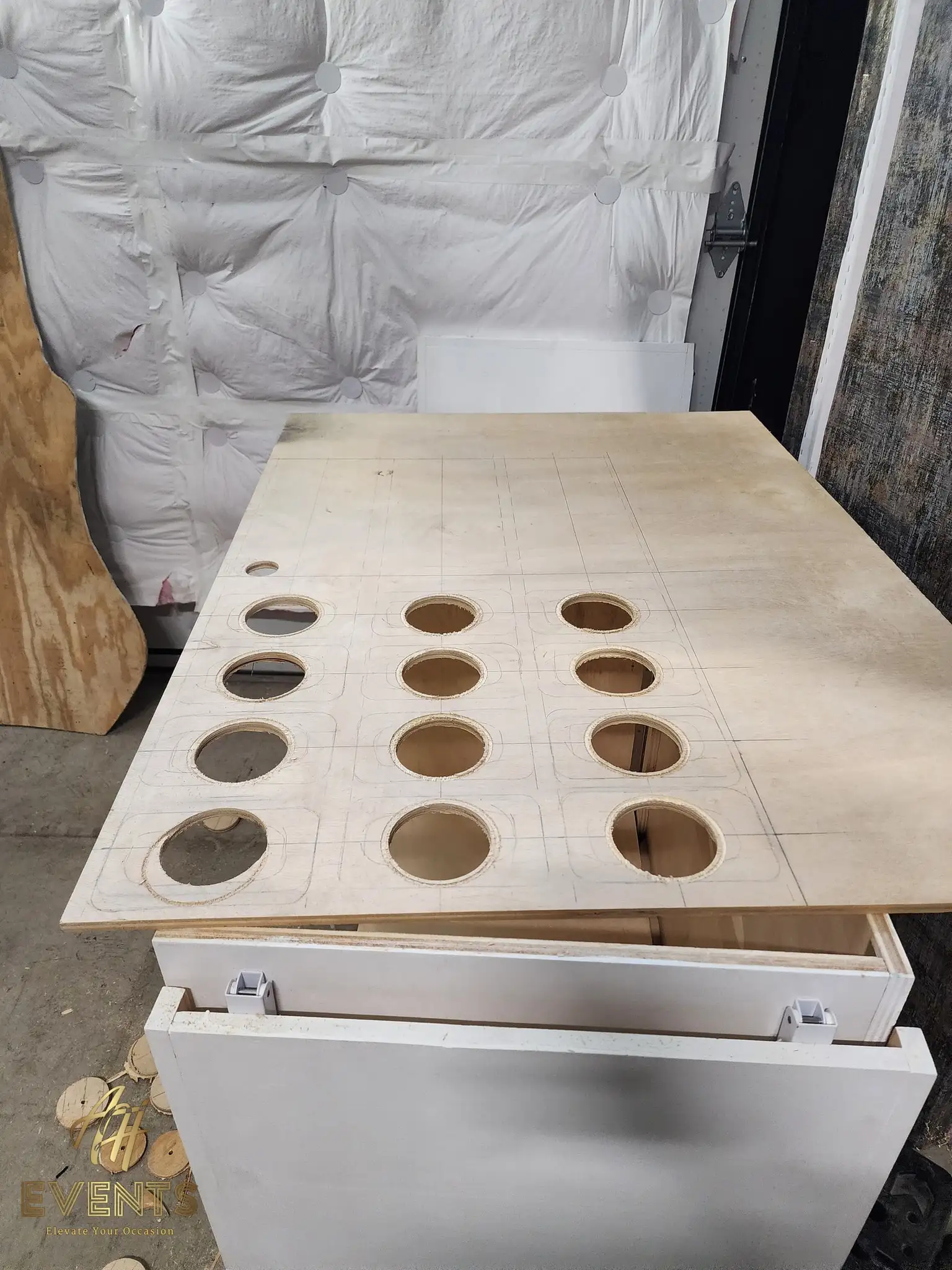 Plywood cart top with circular cup holes cut through in a grid, resting on the white cart base