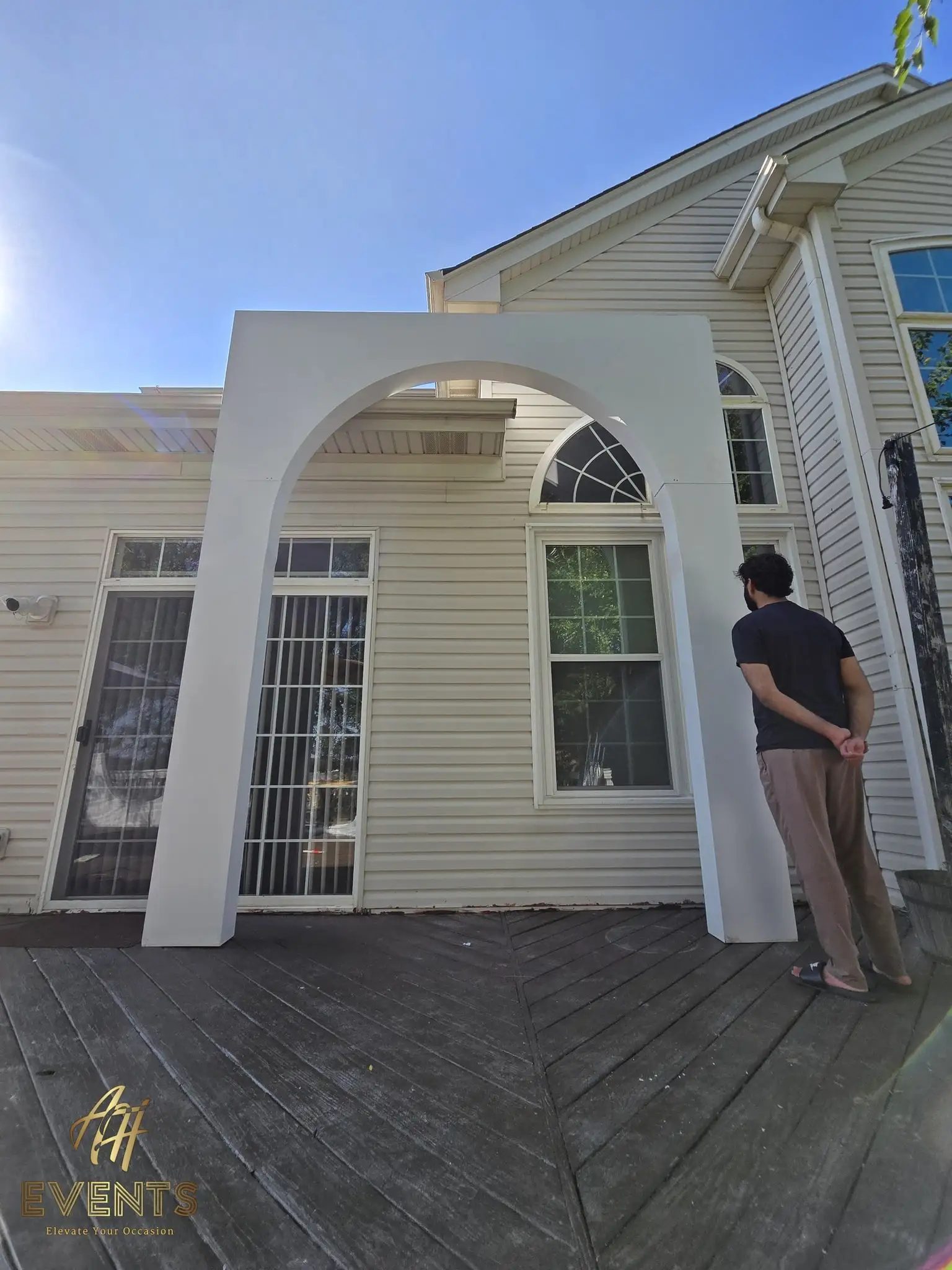 Tall white volumetric arch beside a person for scale on a backyard deck