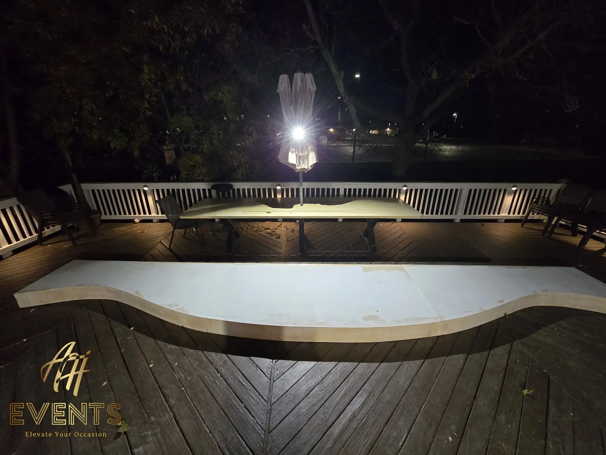 Serpentine white stage riser on a deck at night under deck lighting