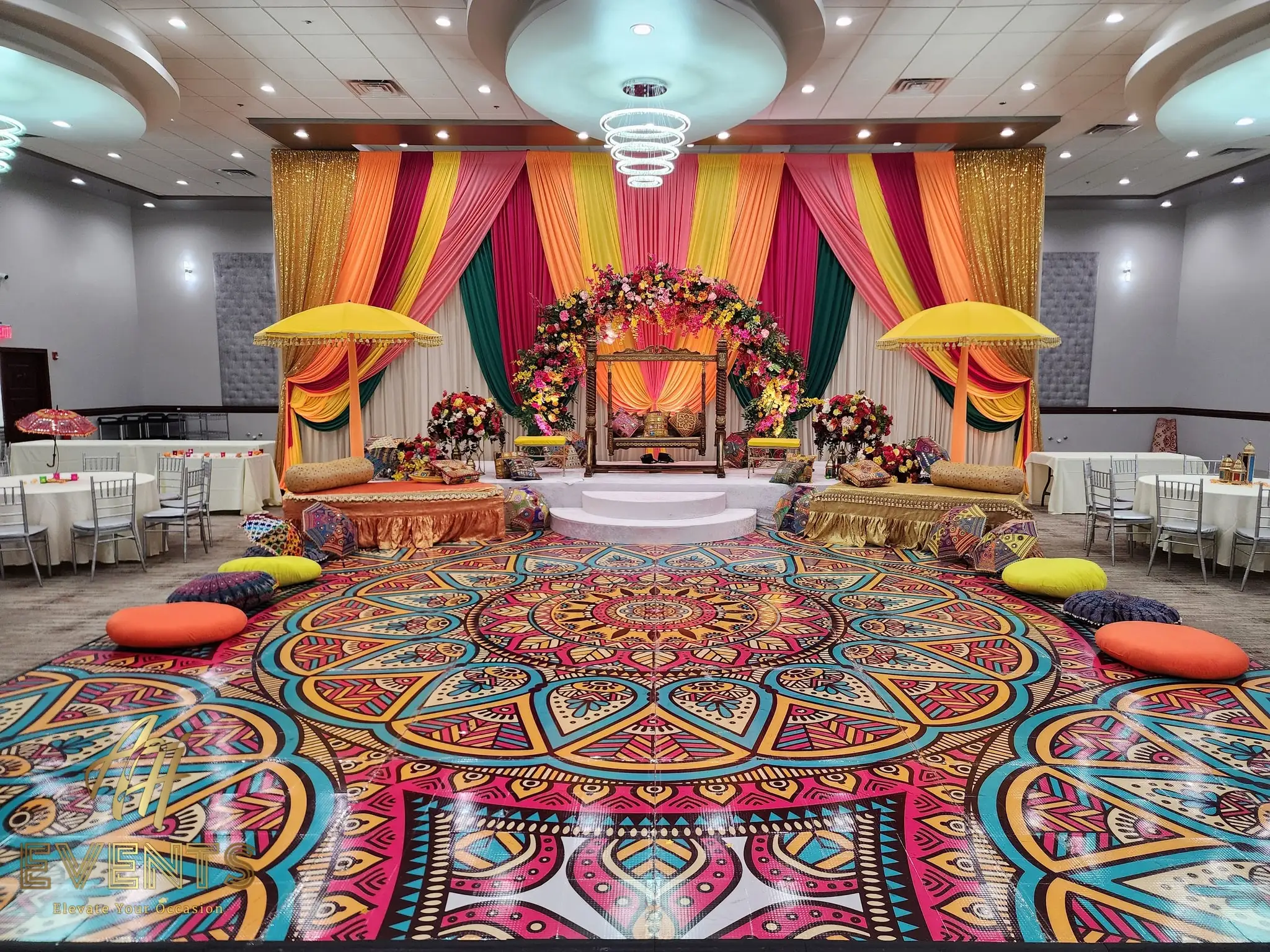Symmetrical mandala dance floor with floor cushions, facing a gold and magenta floral stage