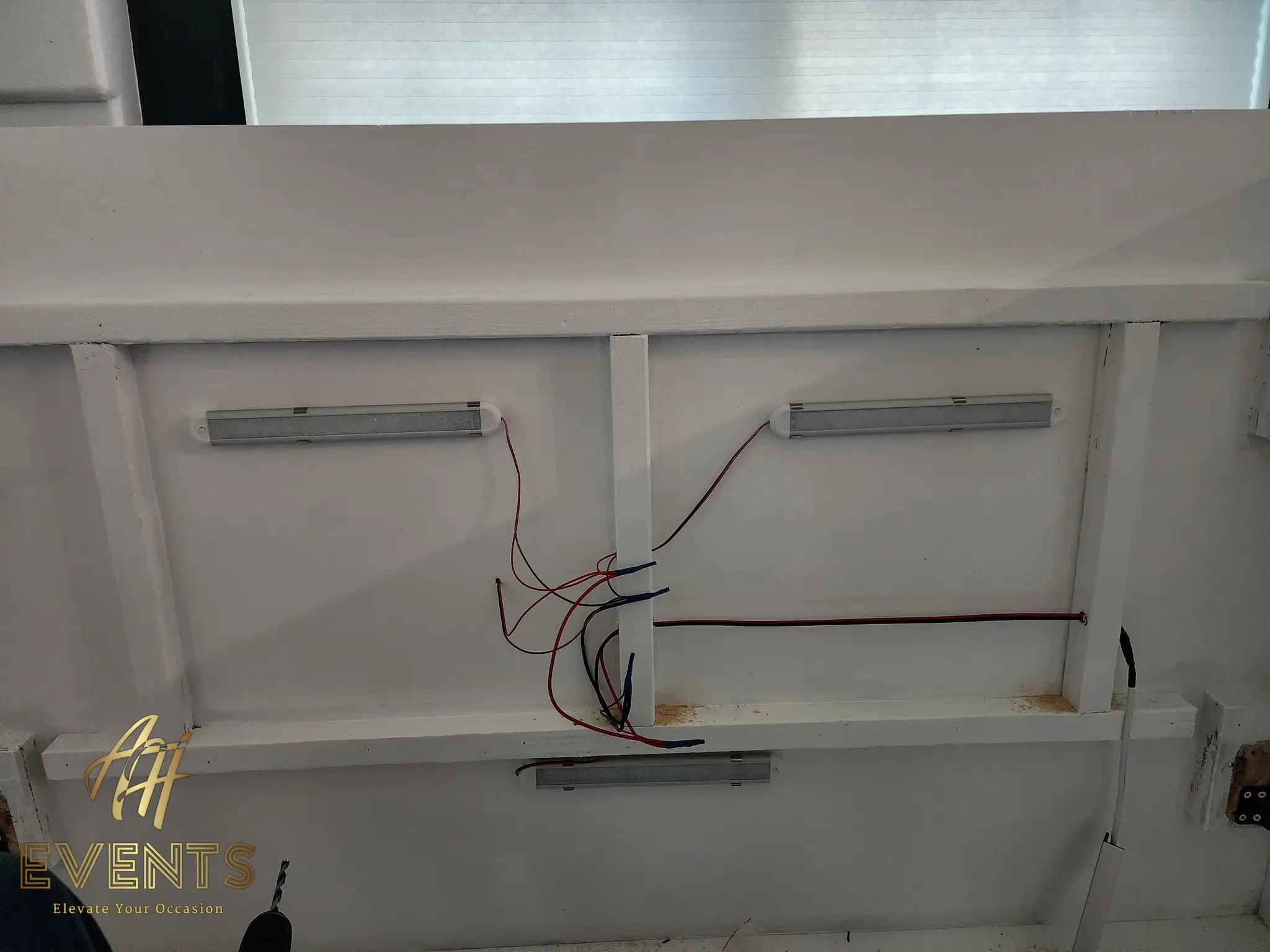 Underside of the AK Desserts canopy during the build, showing mounted LED light bars and exposed red-and-black wiring