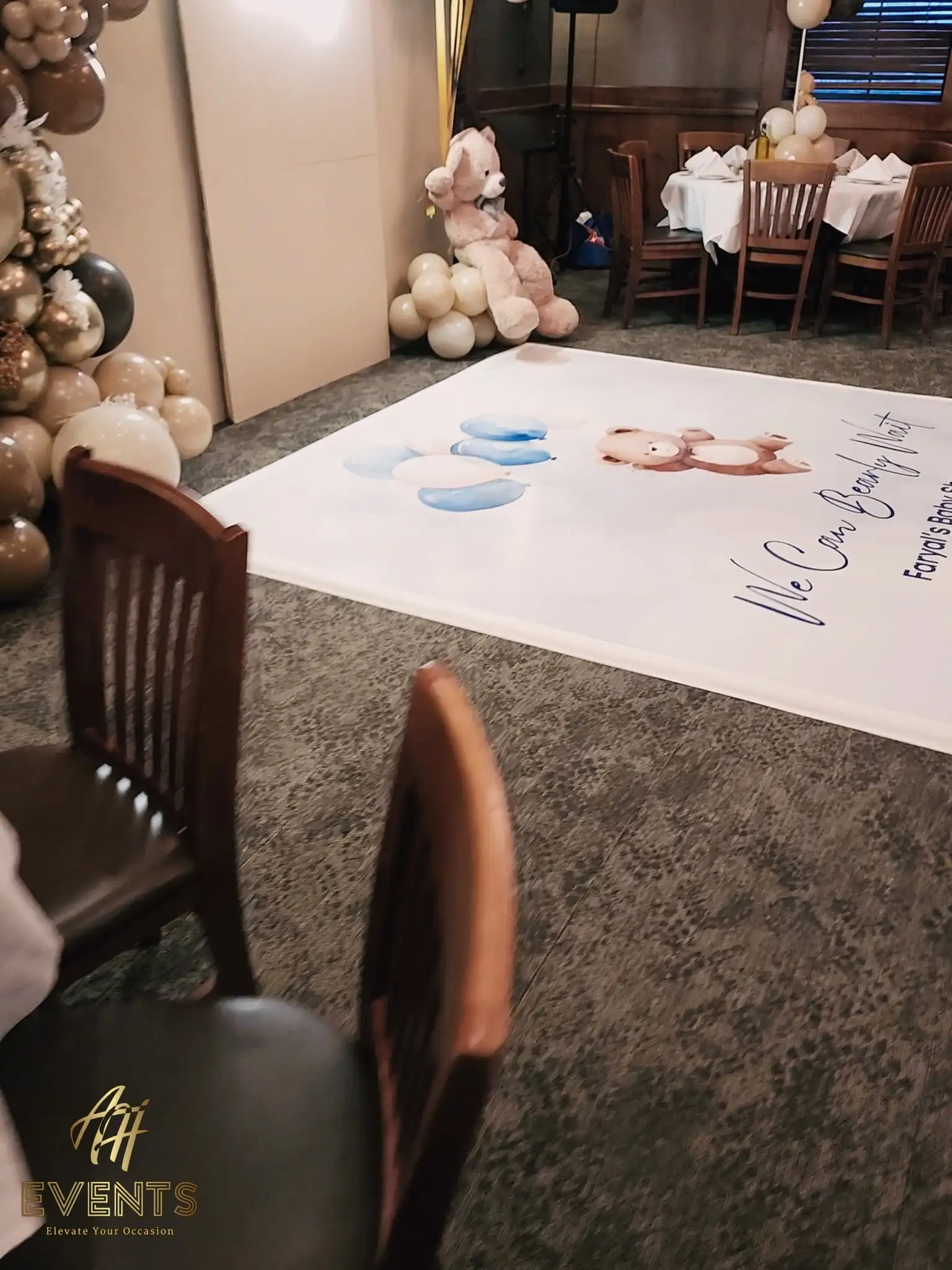 Printed bear baby shower floor decal with a teddy and blue balloons, dining chairs in front and a teddy bear by the arches