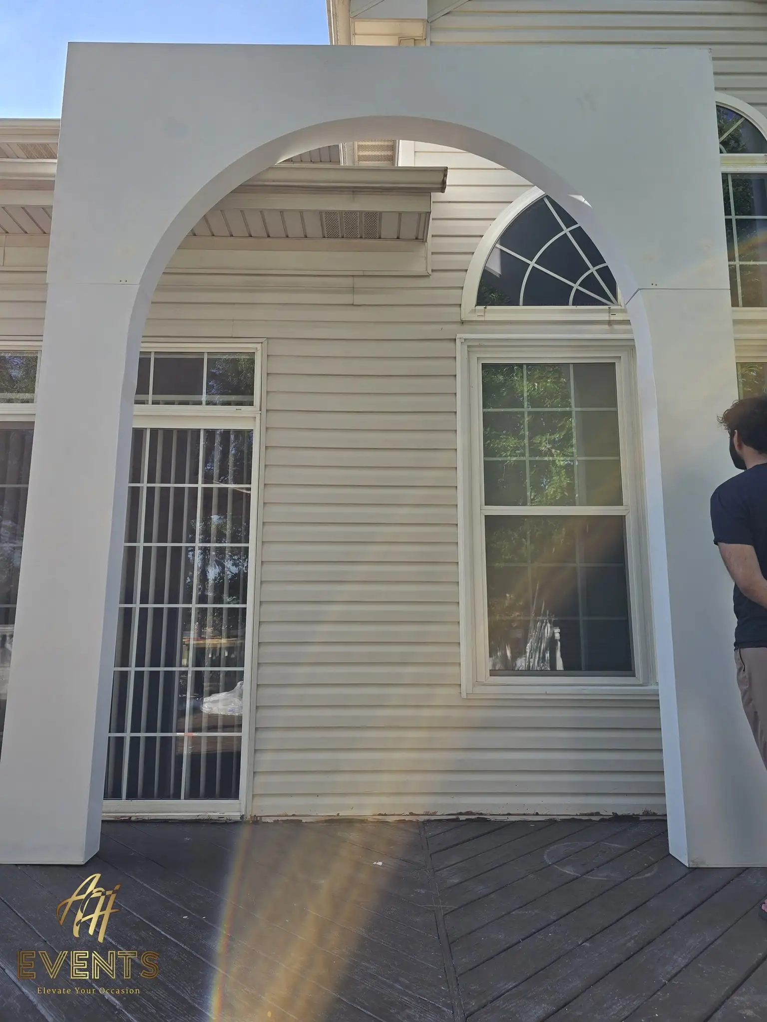 Close view of a white arch's rounded opening against the house siding
